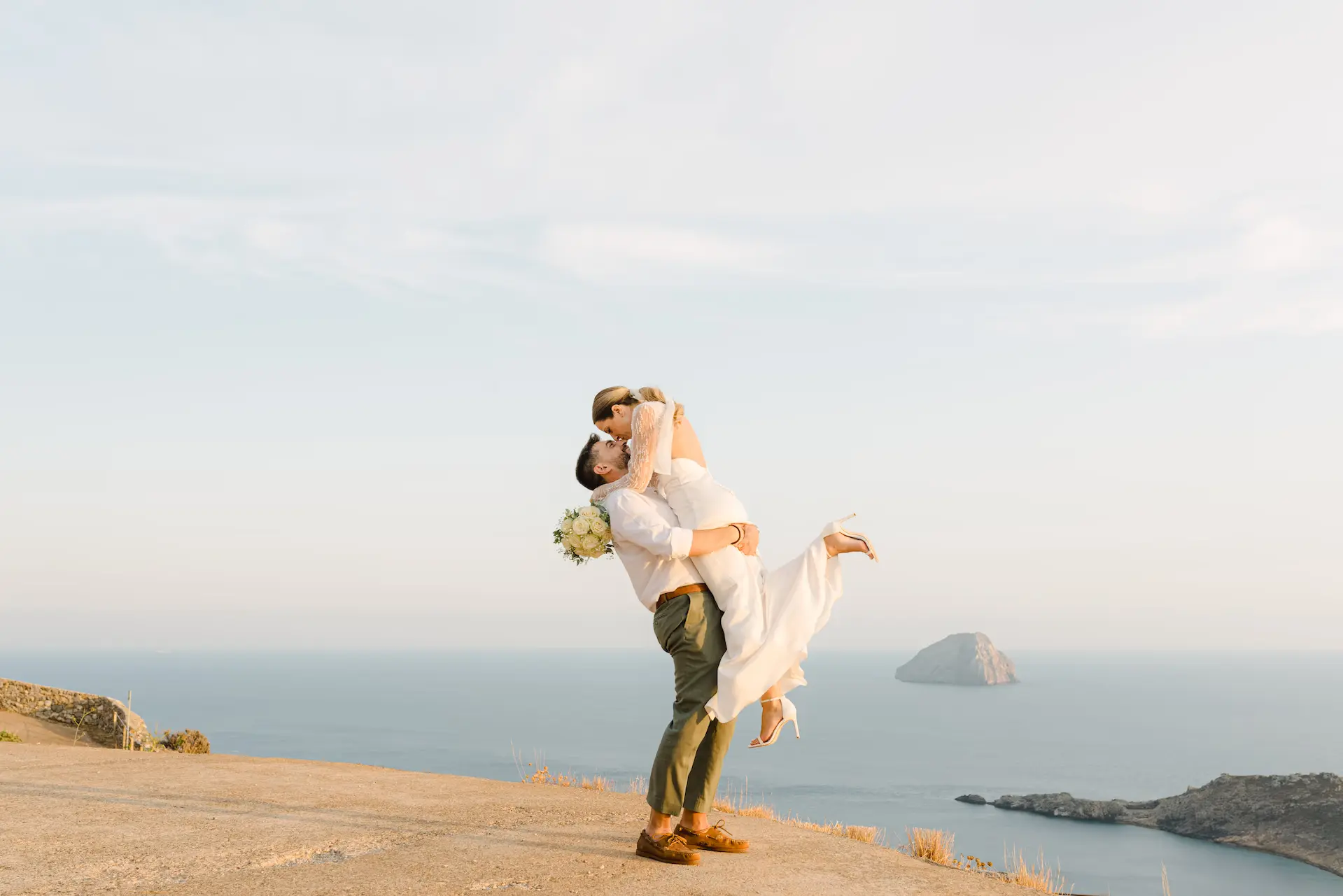 Romantic groom lifting the bride for an emotional kiss during sunset, capturing a pure moment of joy.