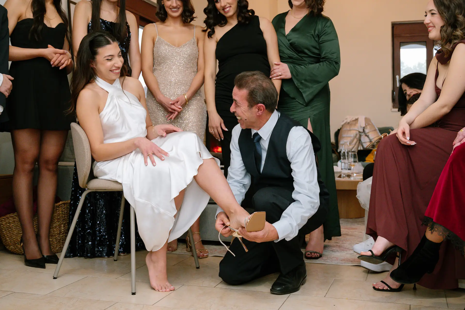 Emotional moment during wedding preparations as the father of the bride traditionality helps his daughter put on her shoe.