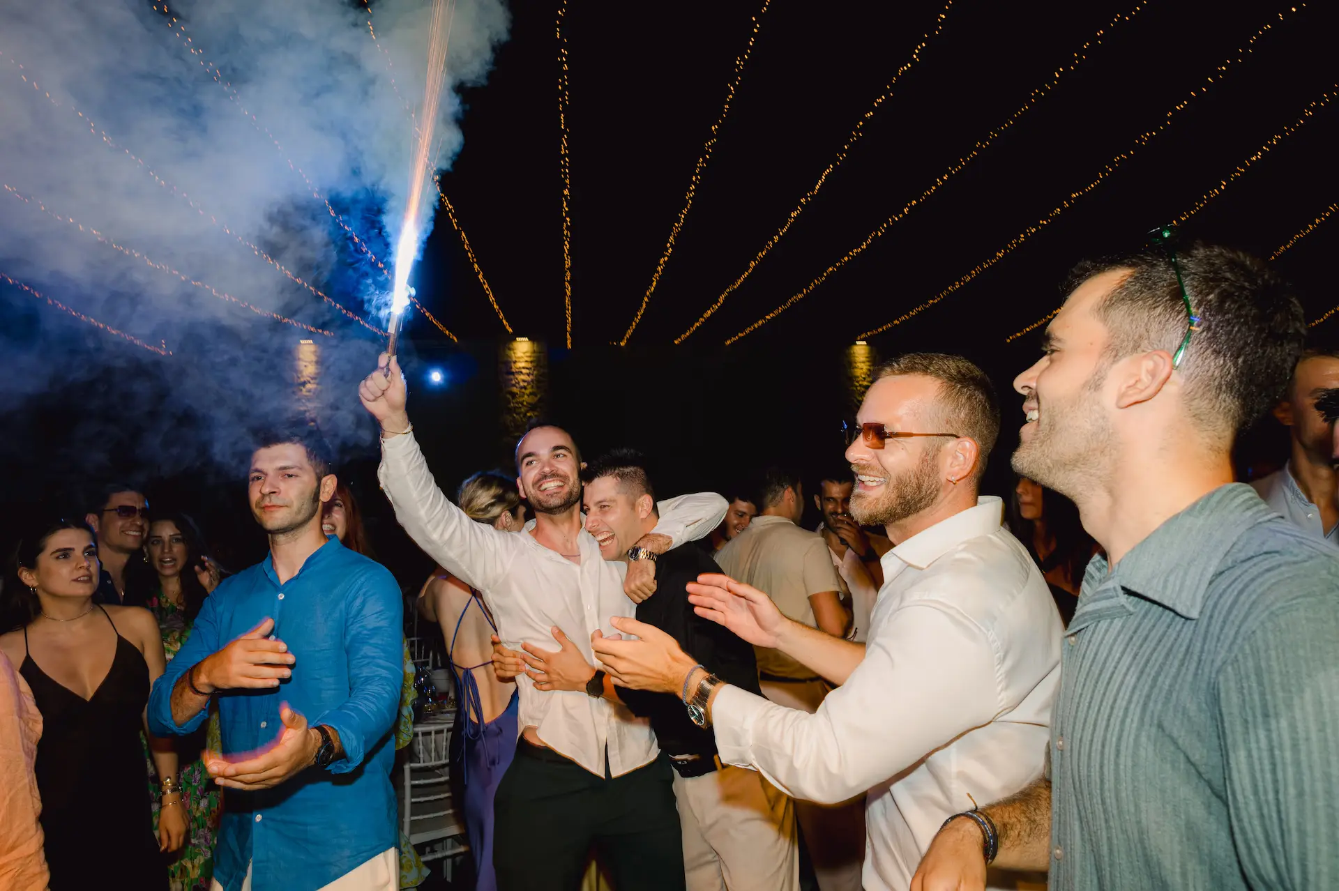 groom with his friends holding fireworks in the dancefloor