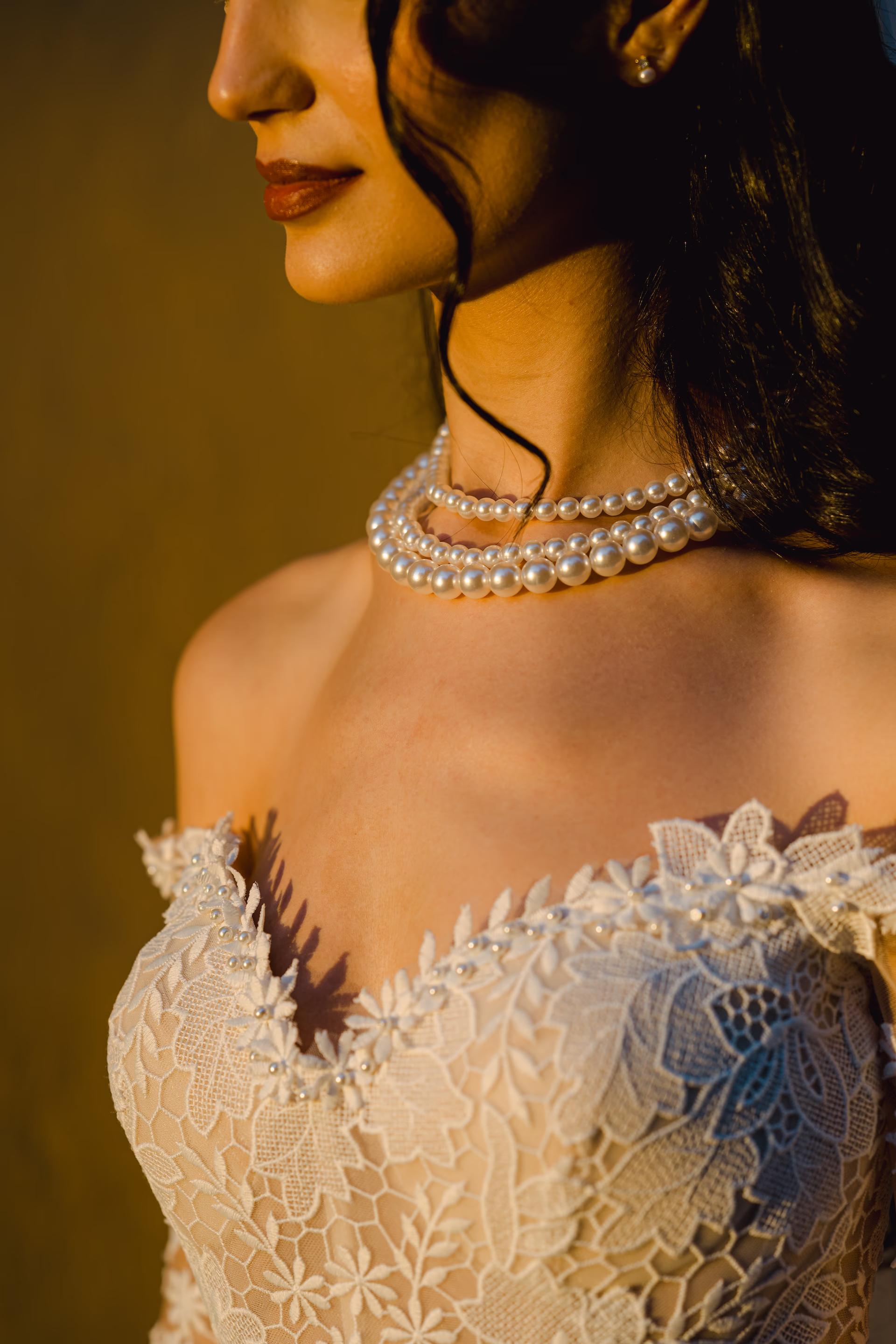 elegant close up of bride's neck with a pearl necklace in sunset light