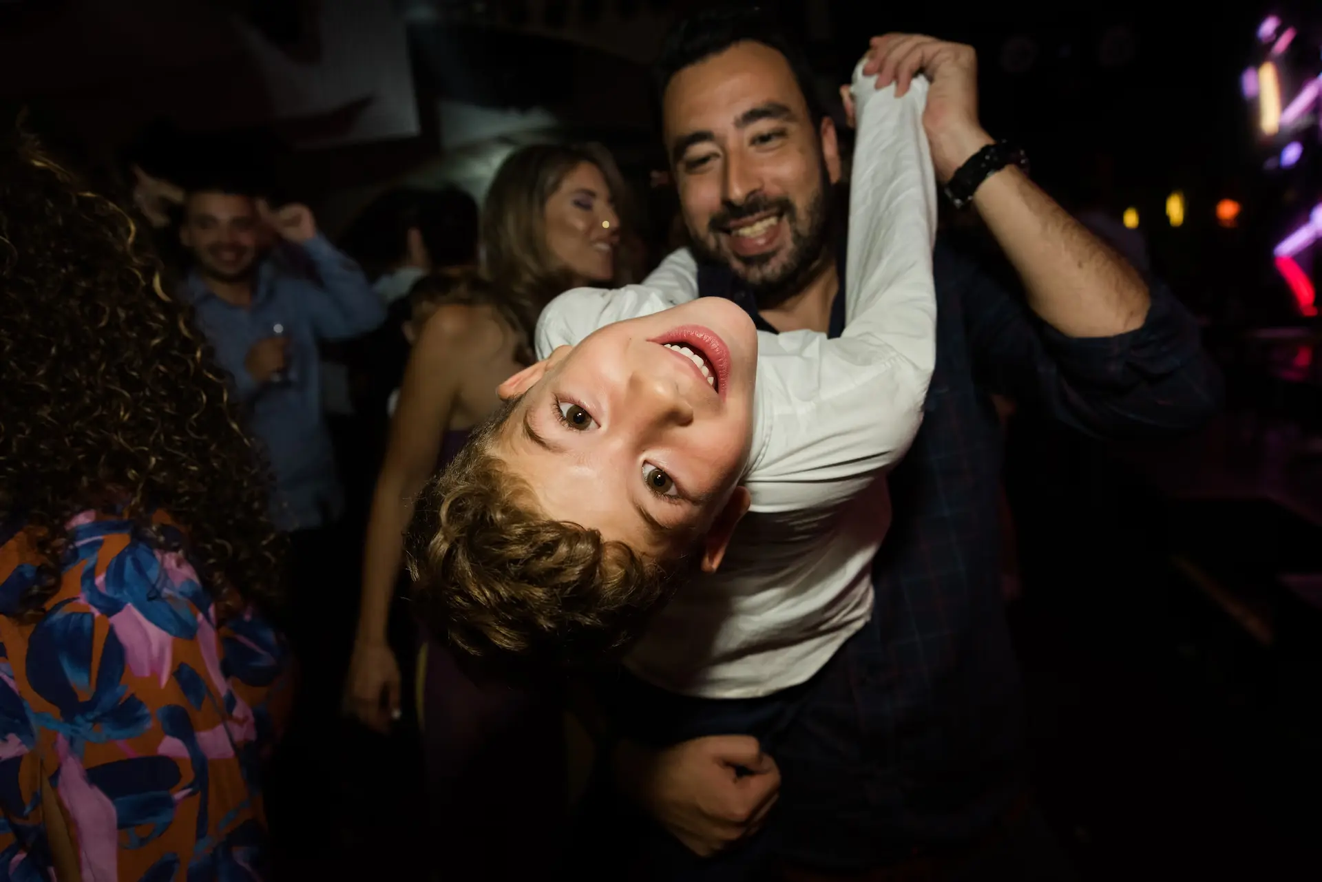 a man holding a boy in his arms in the dancefloor