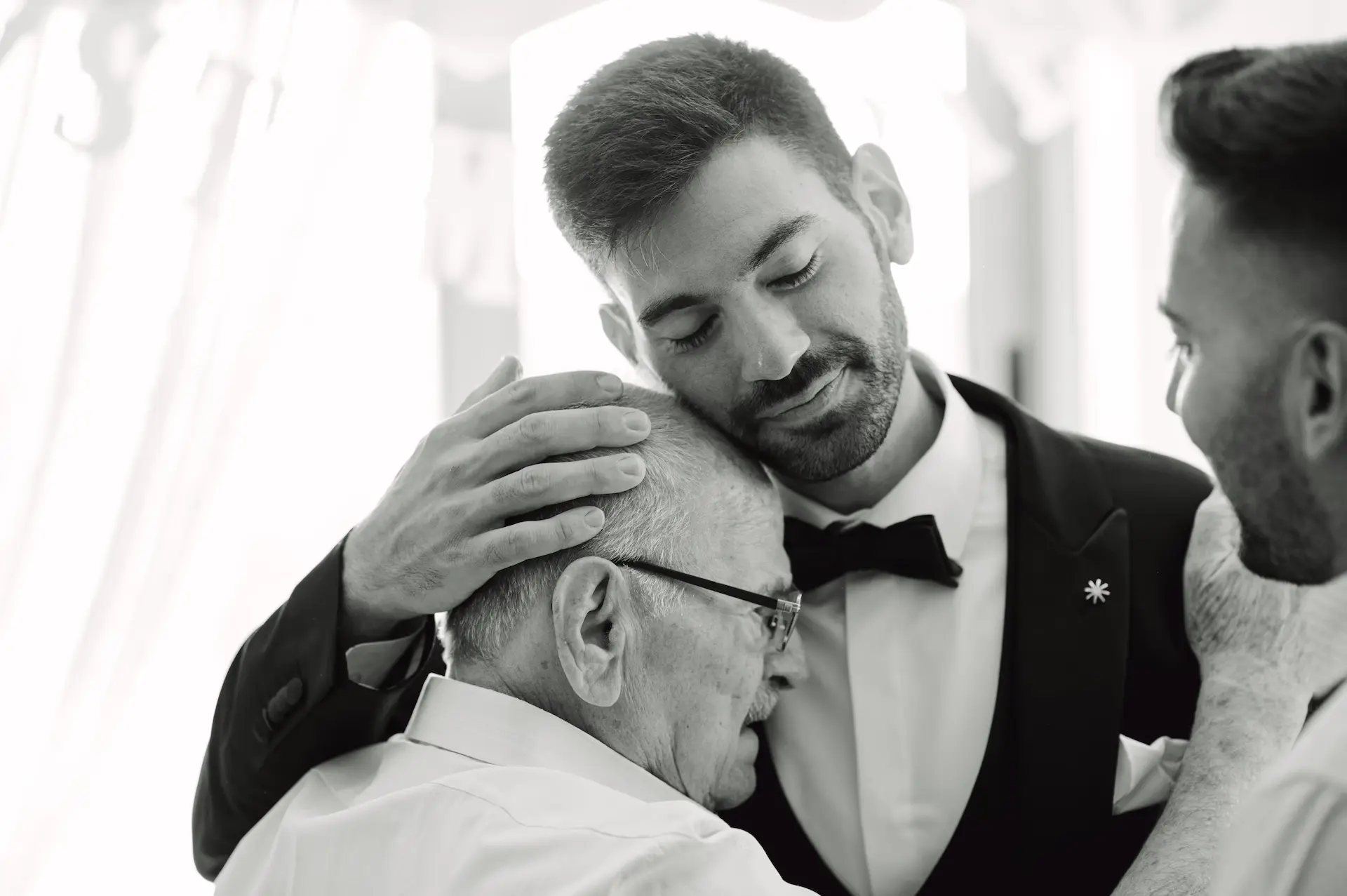 a man in a tuxedo hugging an old man