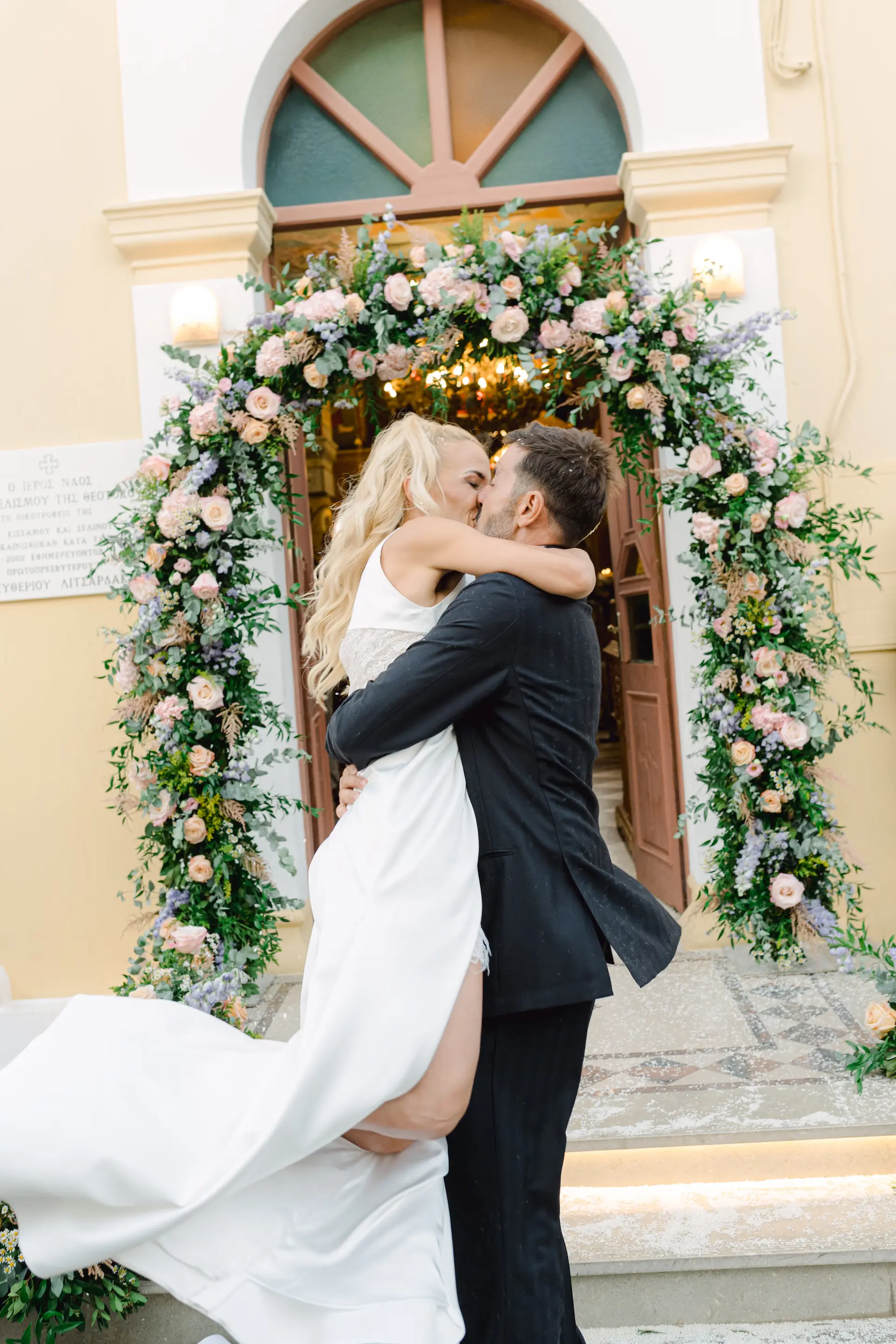 A joyful wedding moment where the groom lifts the bride during their first kiss after the ceremony, capturing pure excitement and love.