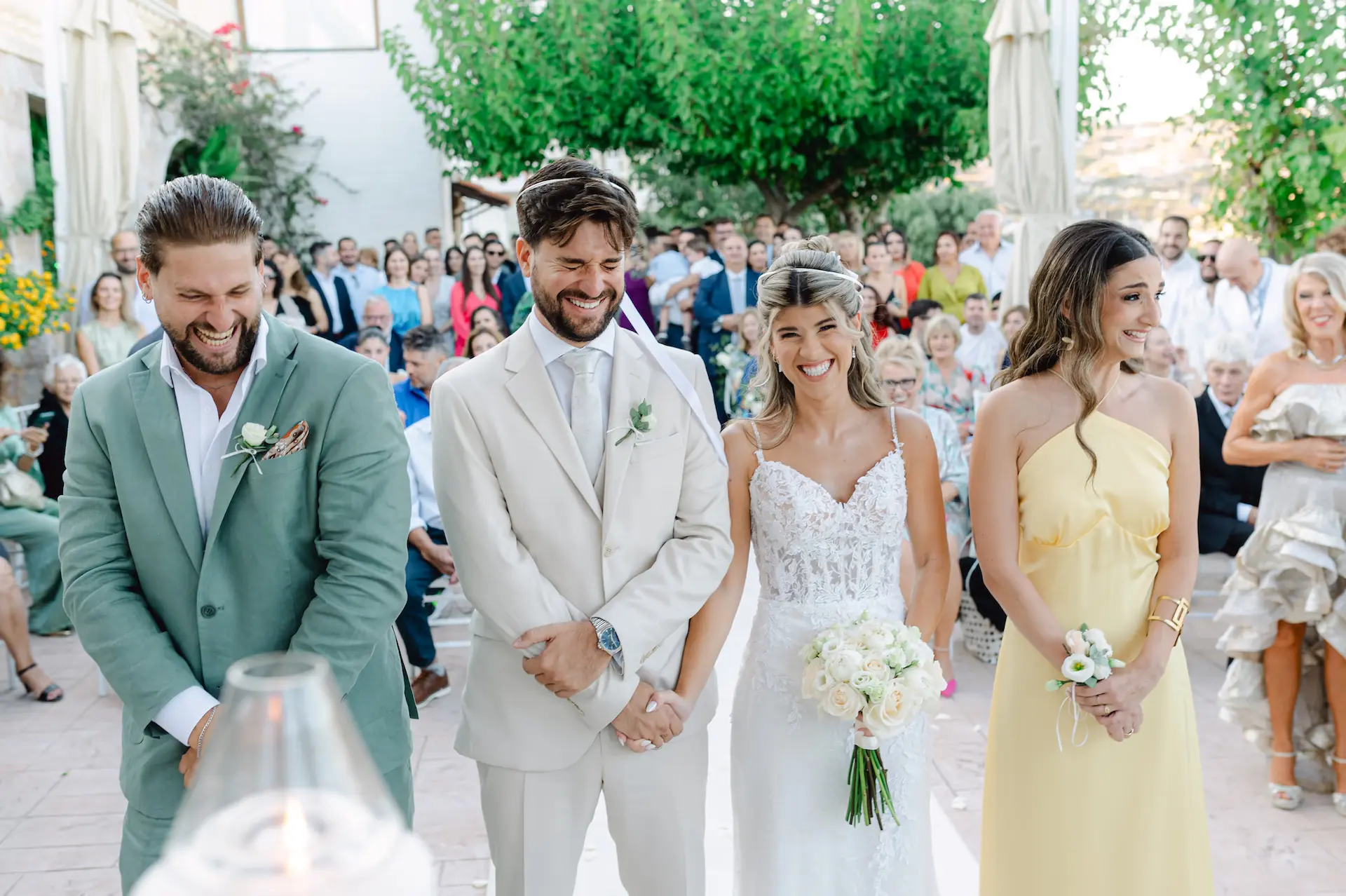 Joyful wedding ceremony moment with the couple and their best man and maid of honor sharing a laugh