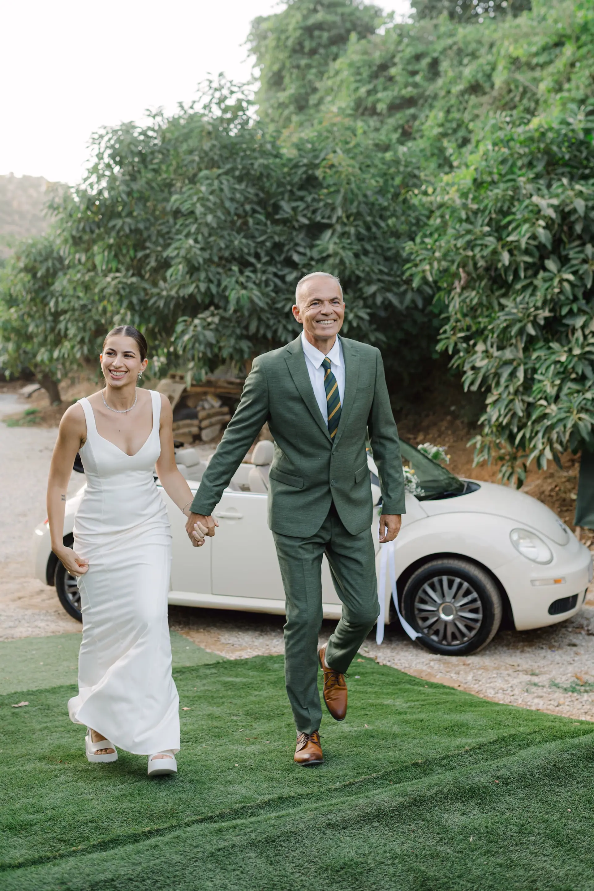 bride and her father holding hands and walking on grass