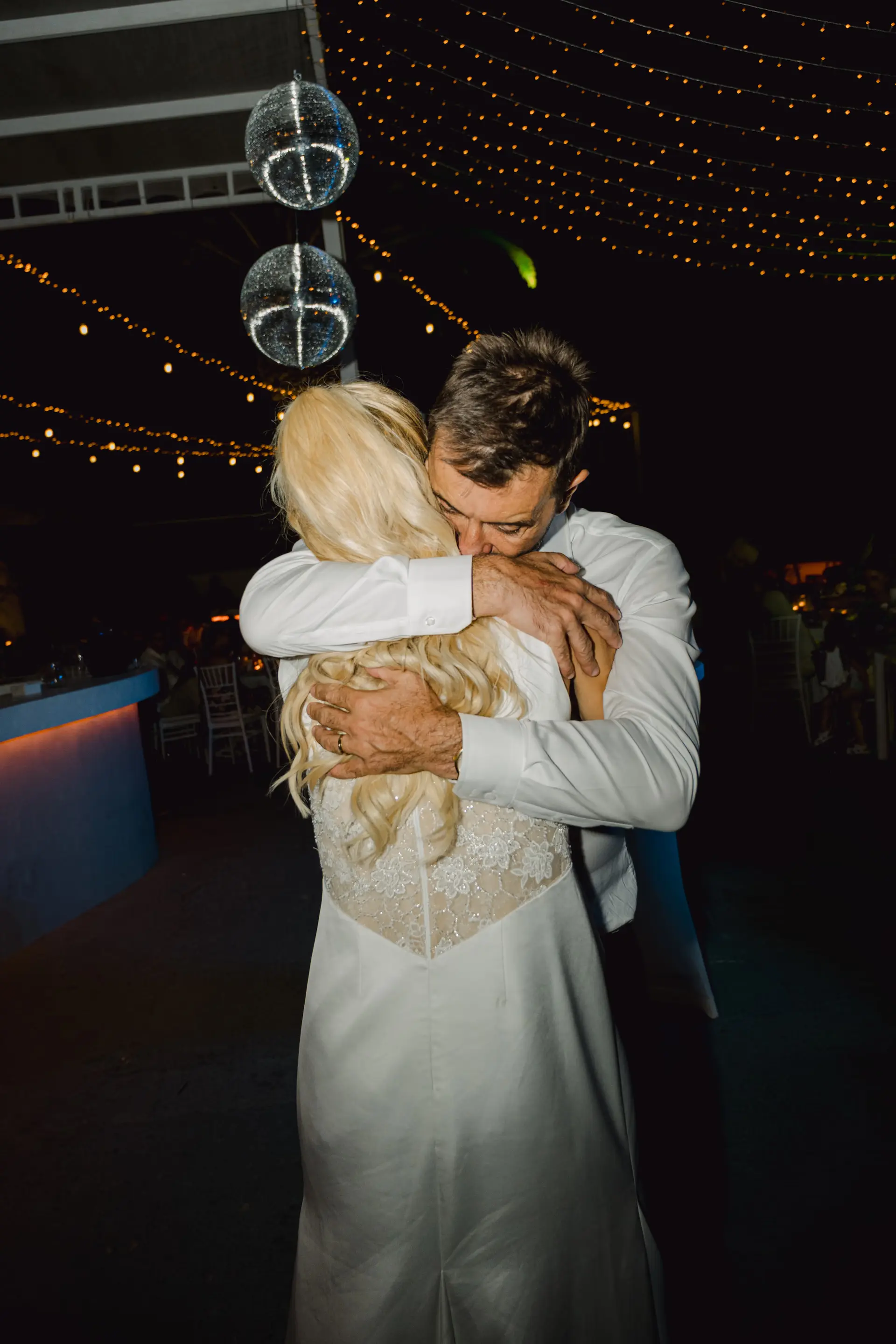Romantic and intense embrace of the newlyweds on the dance floor, highlighting the vibrant energy of the wedding party