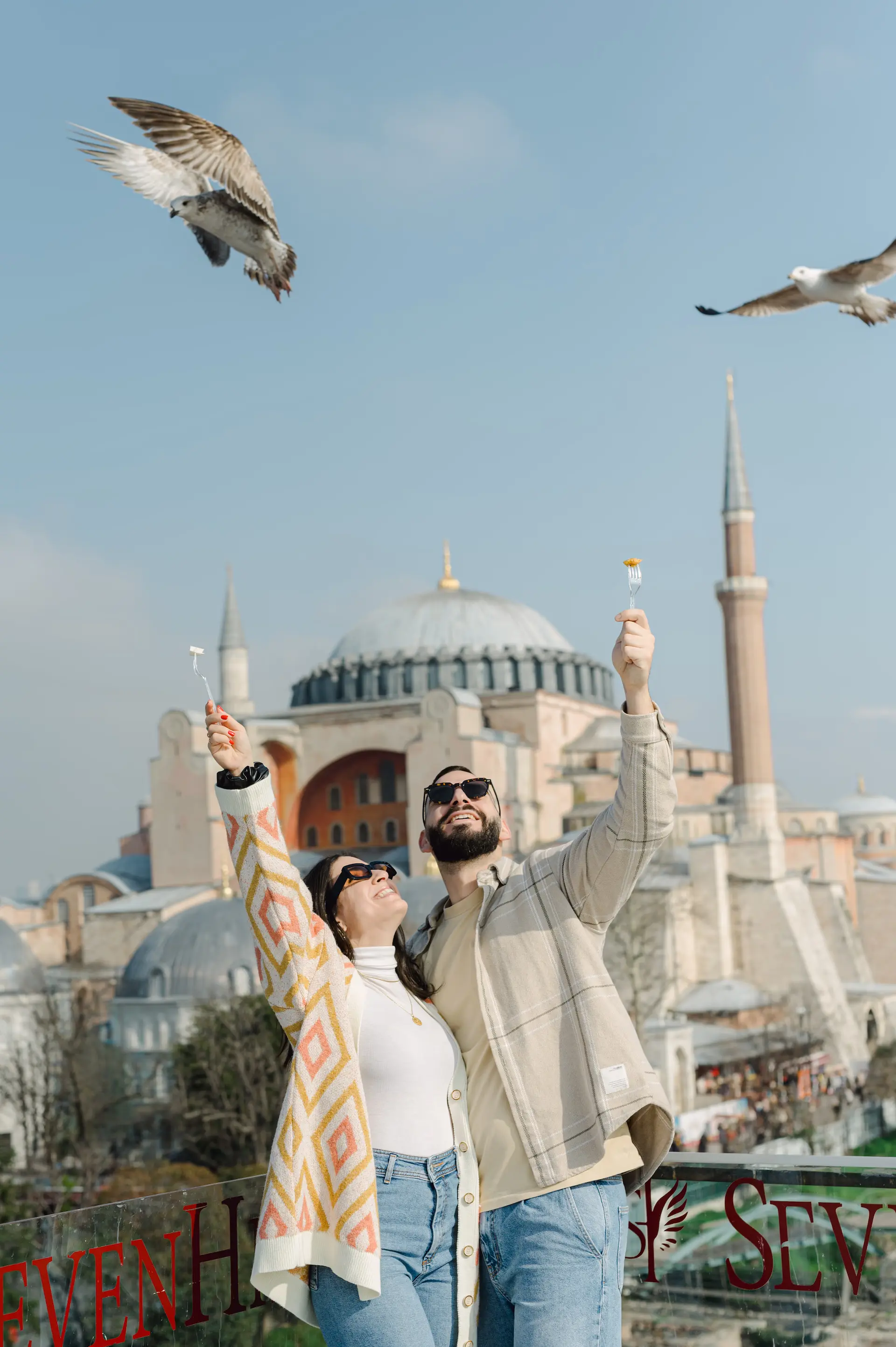 a man and woman holding soap bubbles in front of a building with birds flying