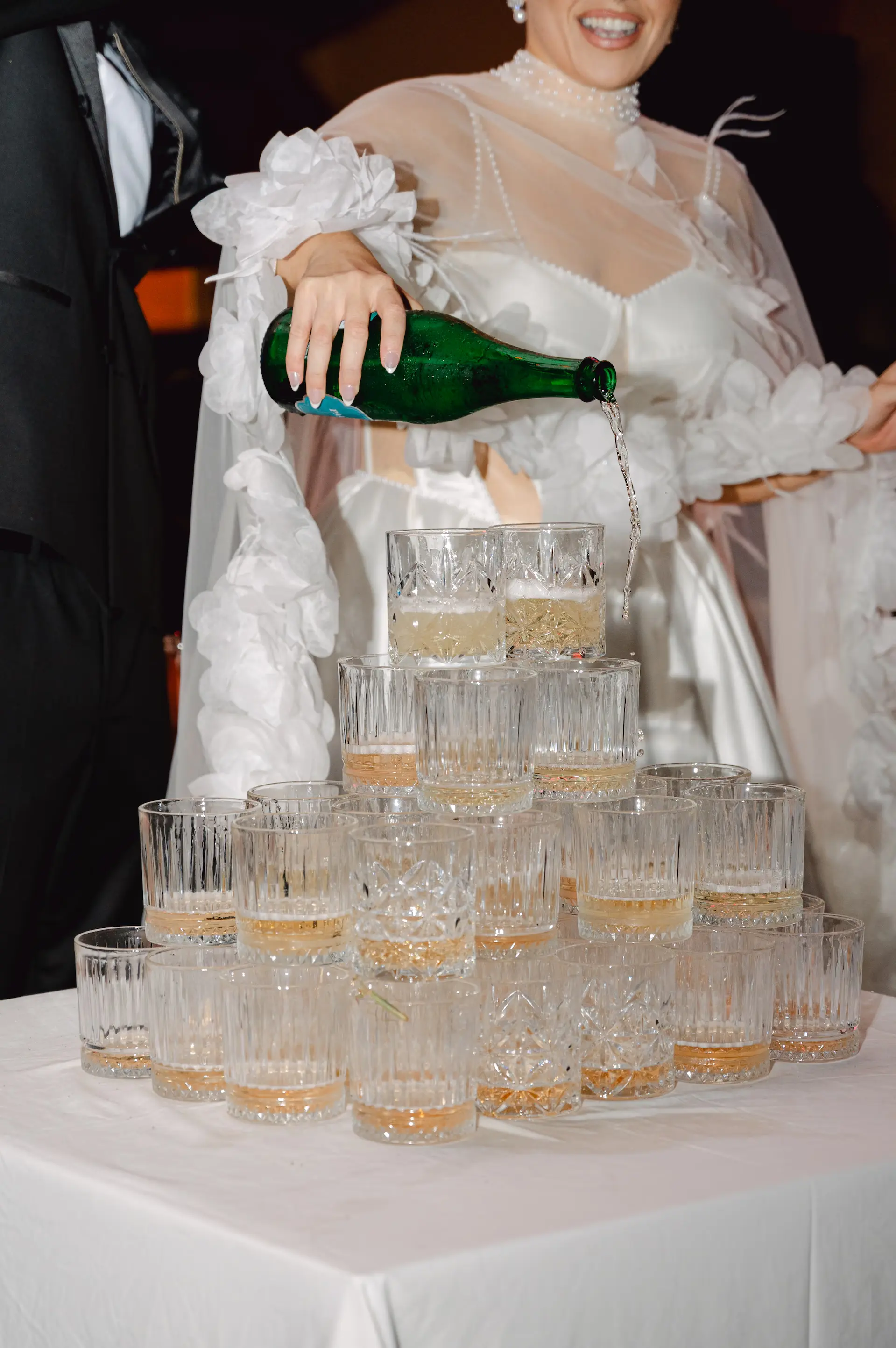 Joyful bride pouring champagne for her guests at the Alkion wedding reception