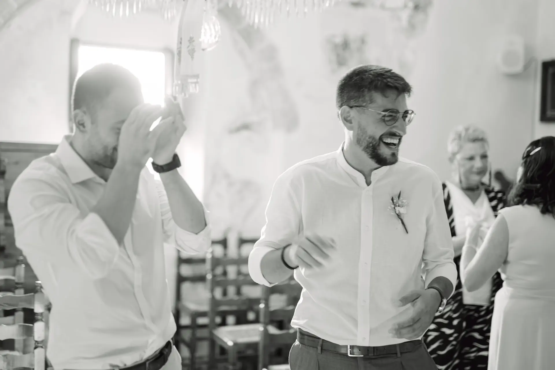 Candid shot of a groomsman being moved to tears during the couple's vows in a Greek island wedding.