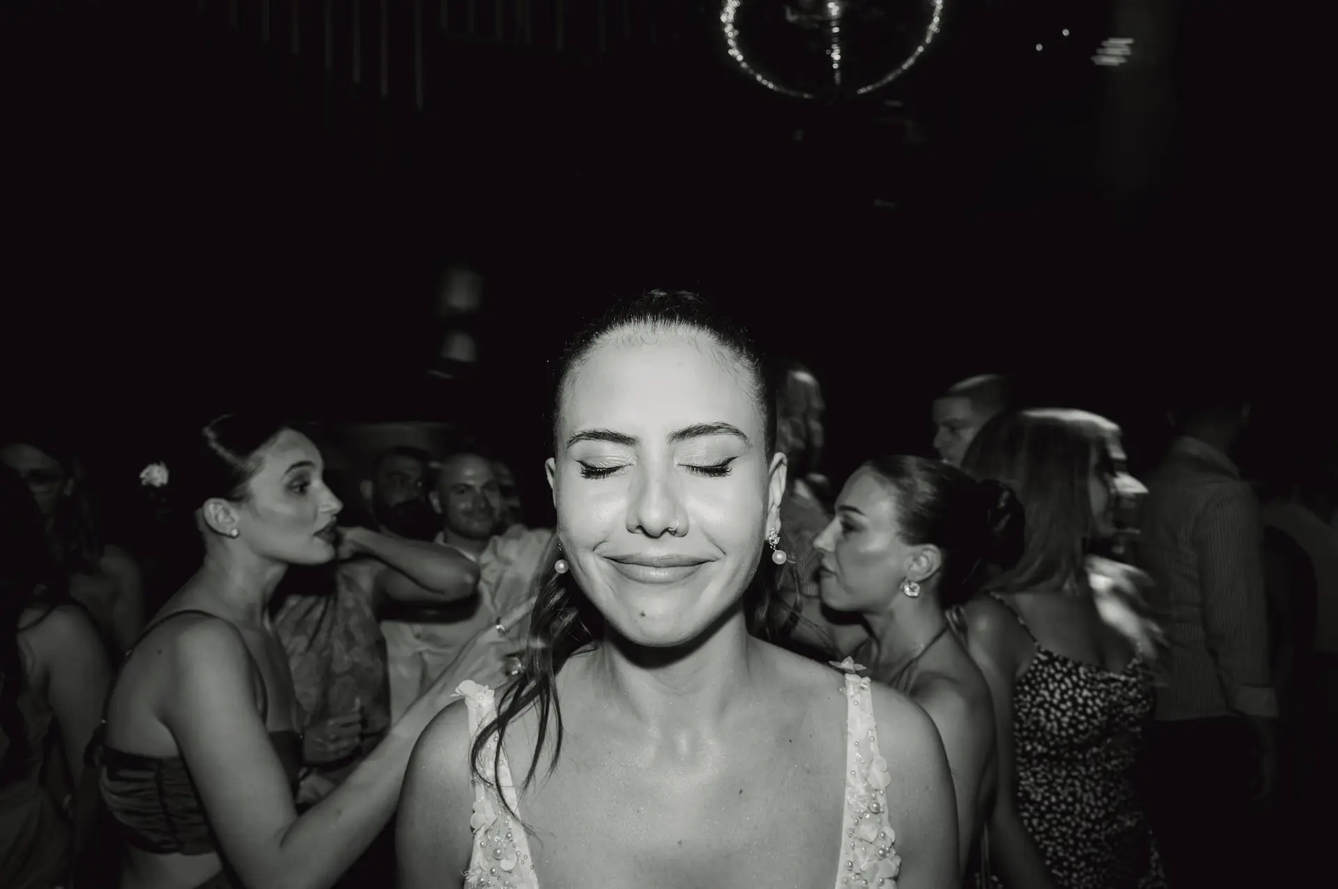 bride portriat with eyes closed and a crowd of people around her