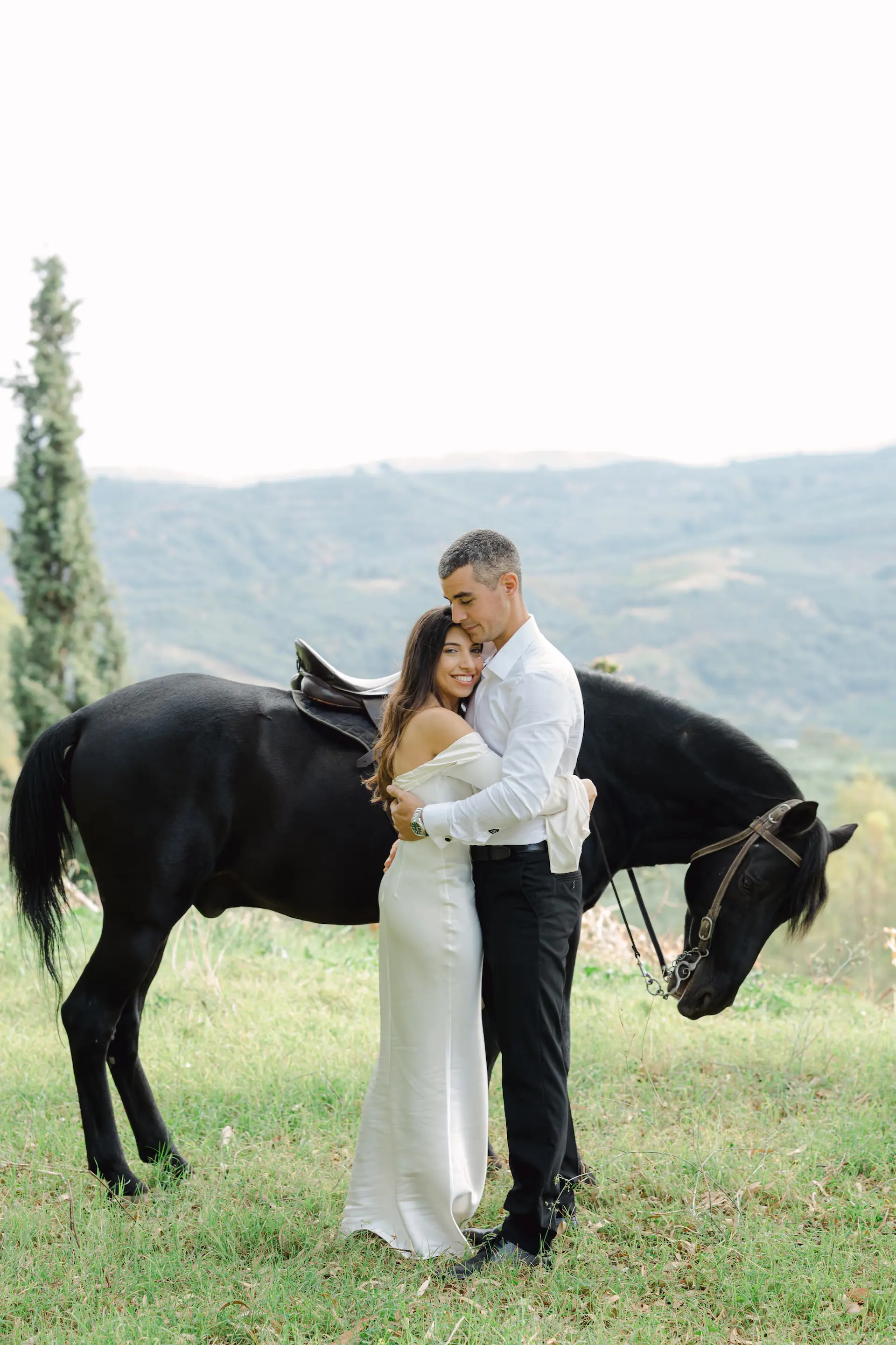 bride and groom sharing a quiet hug next to their horse during a serene next-day wedding photoshoot in nature.