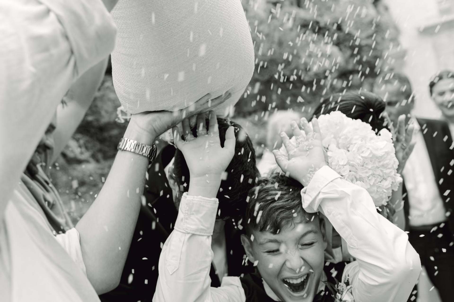 Candid shot of wedding guests throwing rice at the newlyweds, capturing a high-energy emotional moment