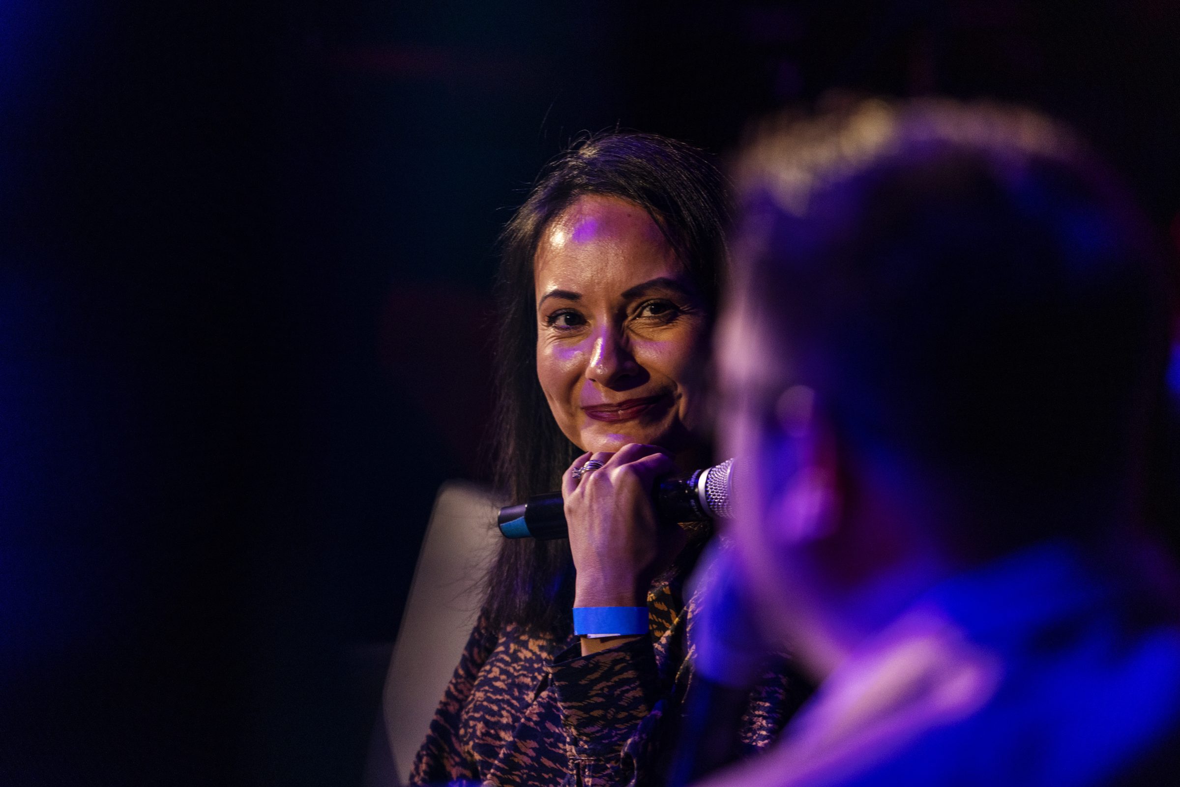 A guest listens and smiles during an on-stage conversation.
