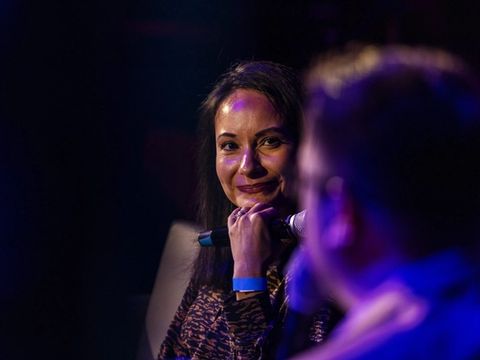 A guest listens and smiles during an on-stage conversation.