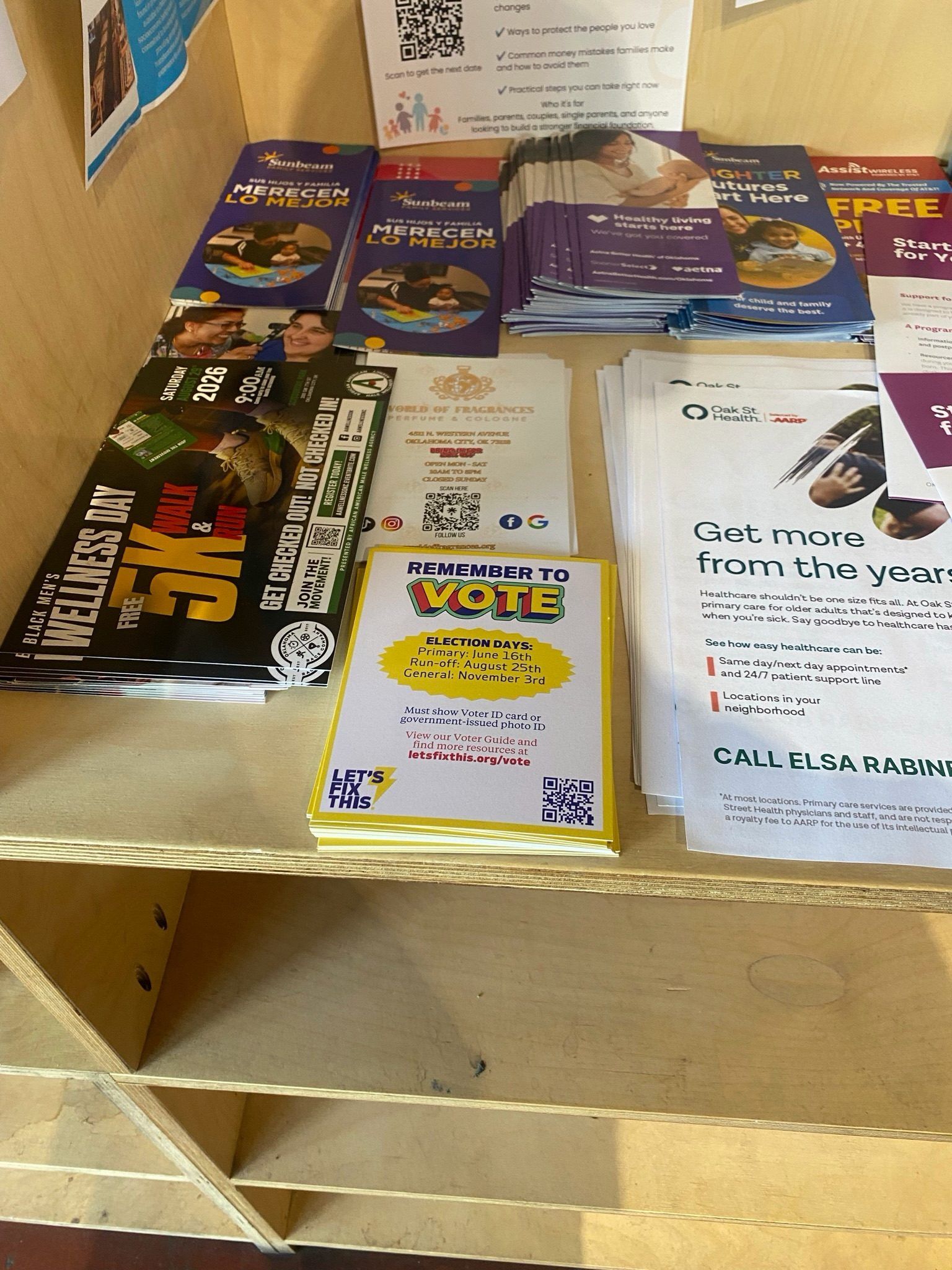 A "Remember to vote" reminder card on a shop counter alongside community flyers.