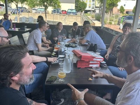 Friends talk across a long patio table with drinks.