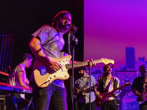 A band plays on a purple-lit stage in front of a projected Oklahoma City skyline.