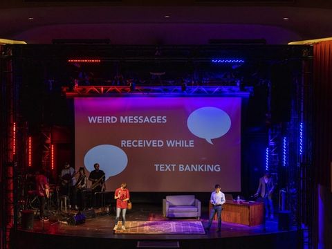 A wide view of the stage and a big screen reading "Weird messages received while text banking."