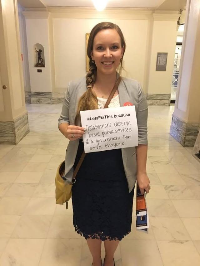 A woman in the Capitol holds a handwritten "#LetsFixThis because" sign.