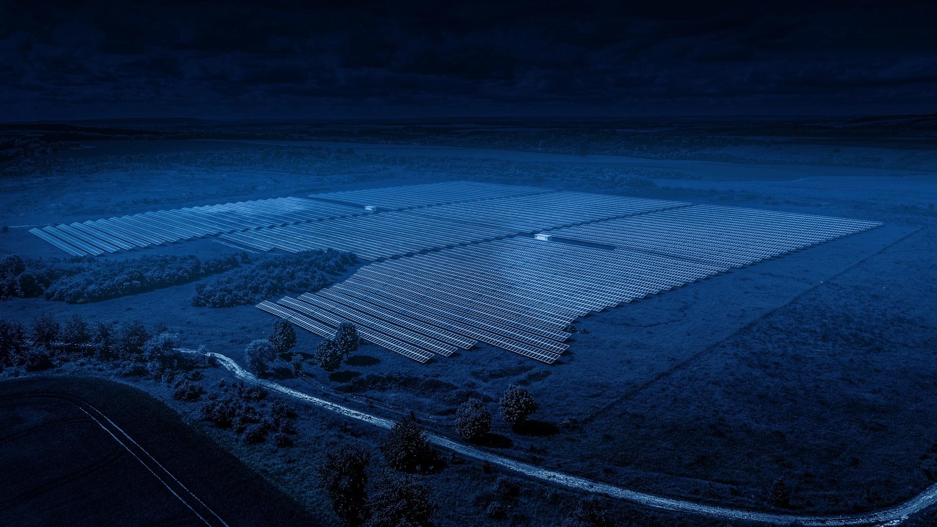 Luftaufnahme eines großen Photovoltaikanlagen-Parks auf einer Wiese.