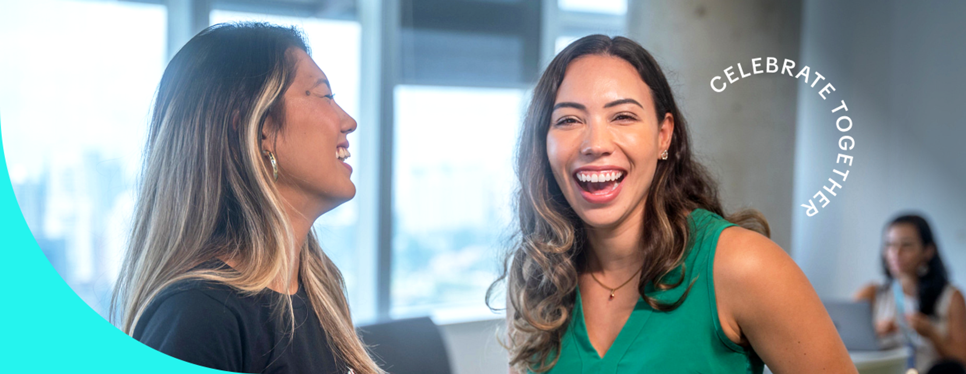 Two young female TikTok employees smile and laugh together.