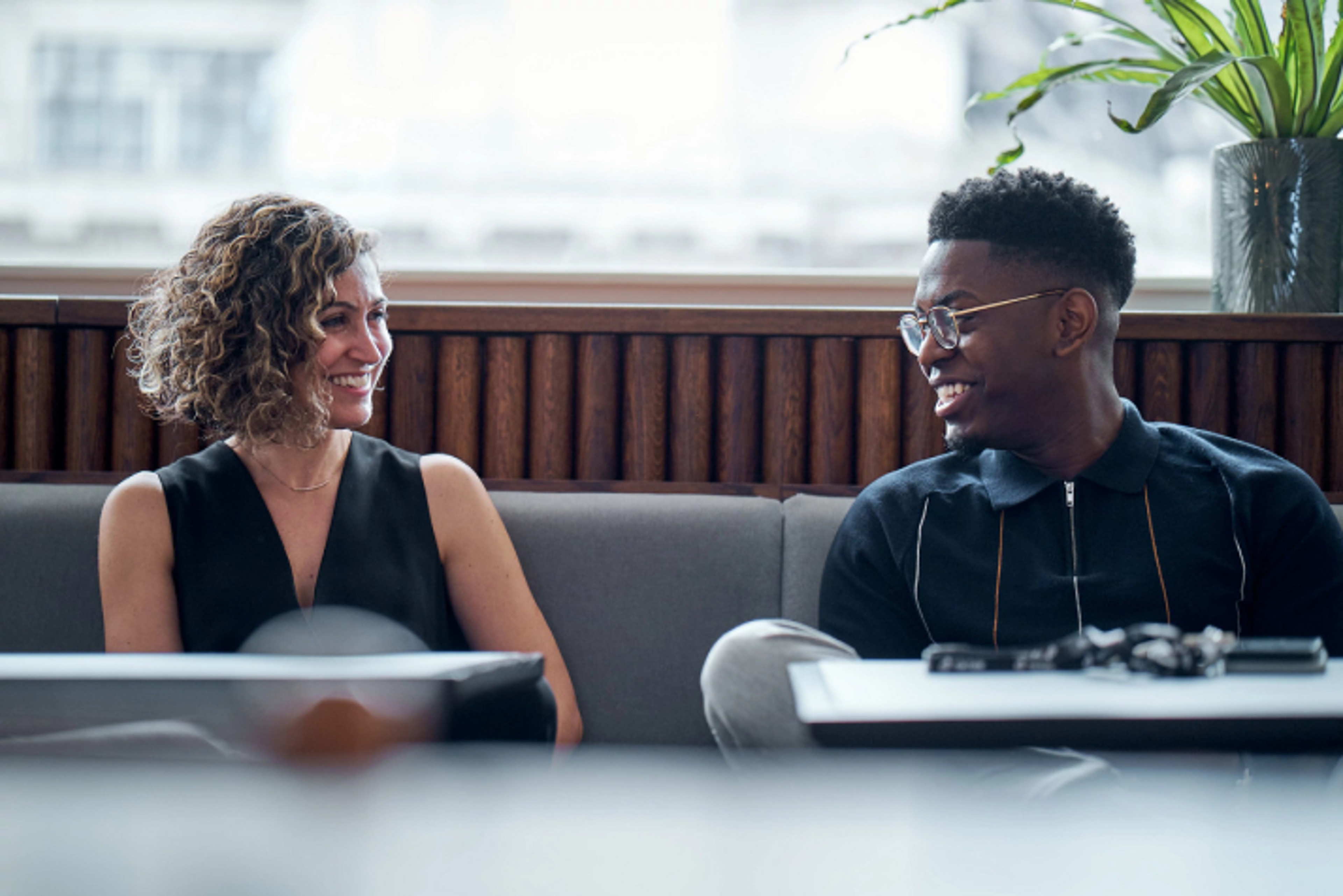 A young male and a female TikTok employee smile as they sit beside each other on a couch.