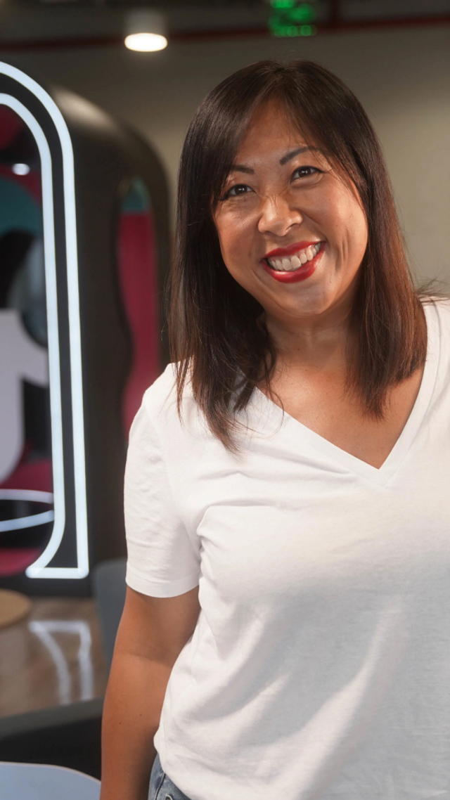 A female Asian TikTok employee smiles as she poses for a photo.