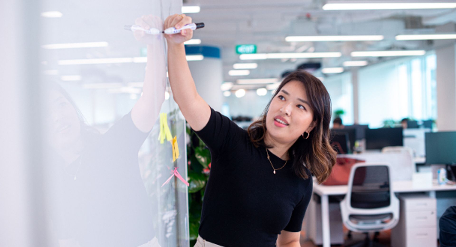 A young Asian female ByteDance Ph.D. Intern writes on a whiteboard.