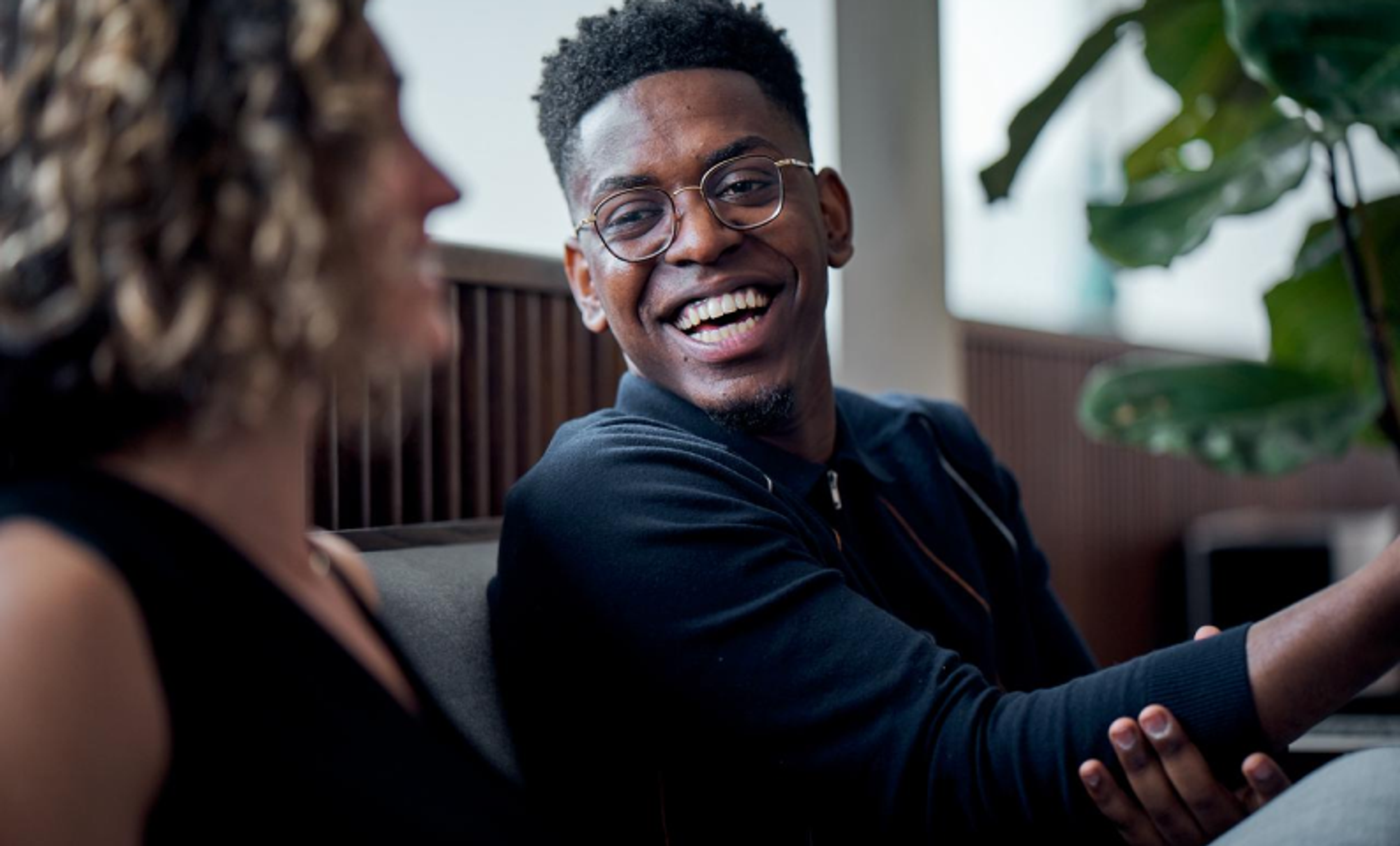 An African American male ByteDance employee laughs and smiles with a female colleague.