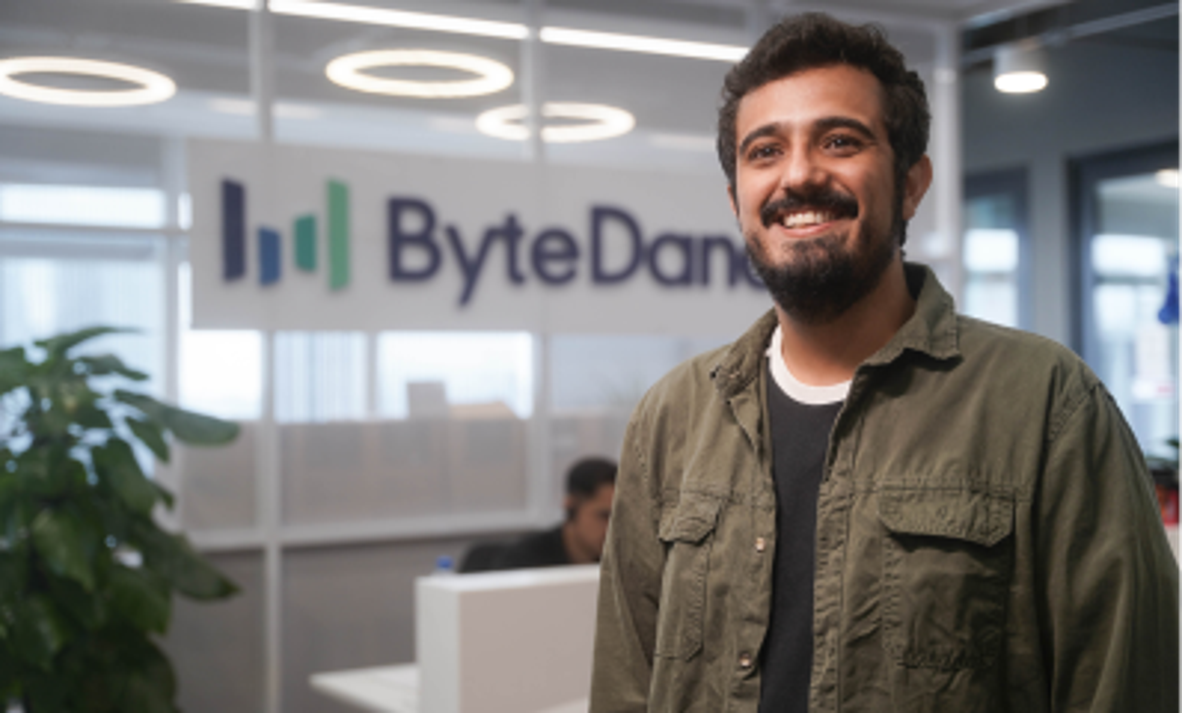  A young male ByteDance employee stands in a ByteDance office and smiles.