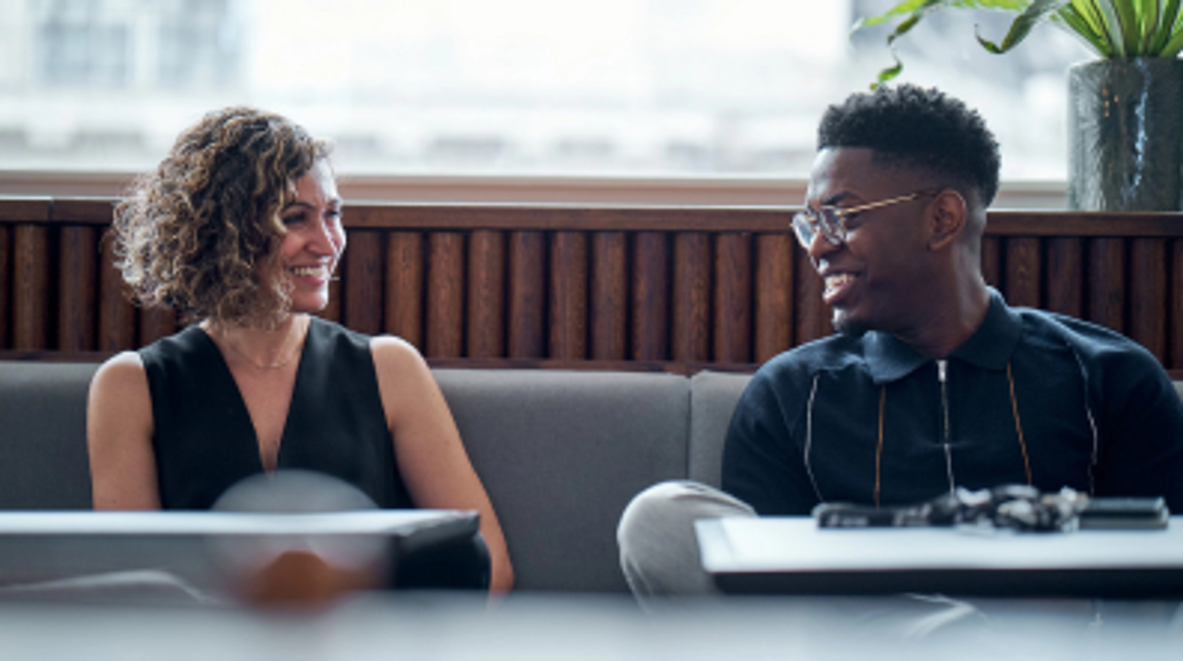 A young male and a female TikTok employee smile as they sit beside each other on a couch.