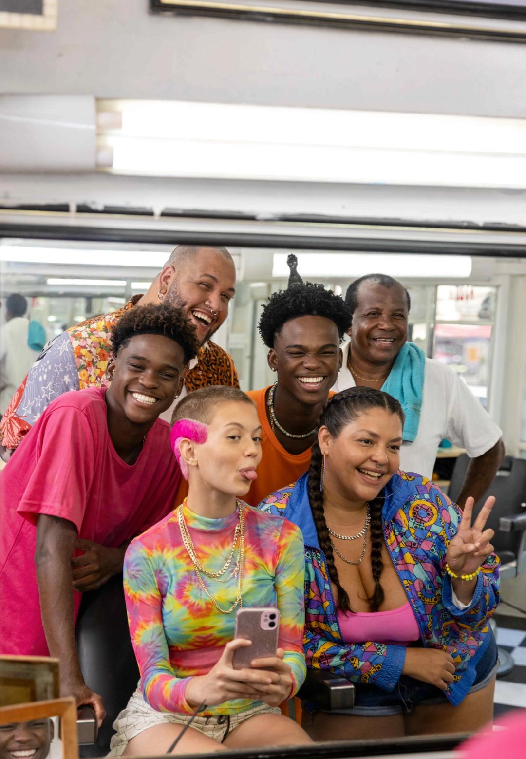 A diverse and multi-generational group of friends smile and laugh as they take a selfie together.