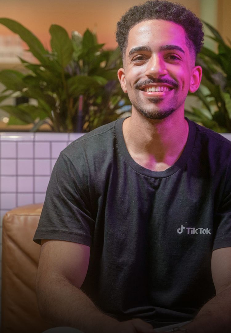 A young Black TikTok employee smiles as he poses for a photo.