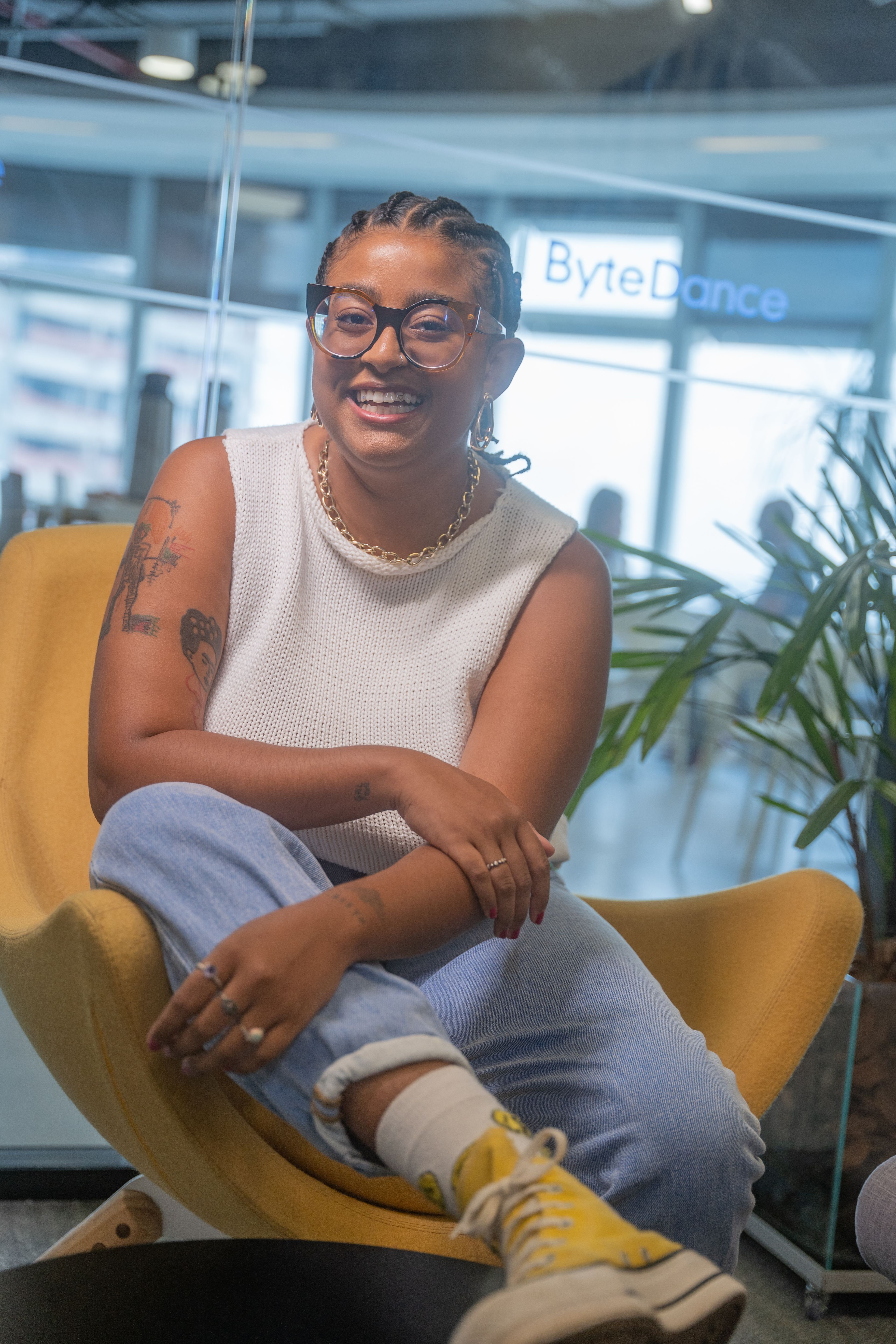 A young female ByteDance employee sitting on a yellow chair and smiling.