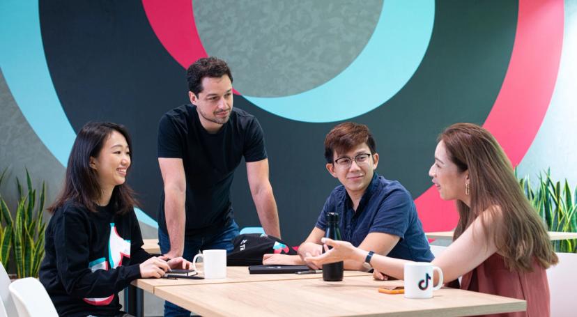 Five participants in TikTok's Working Students Program sit and work together in an office setting.