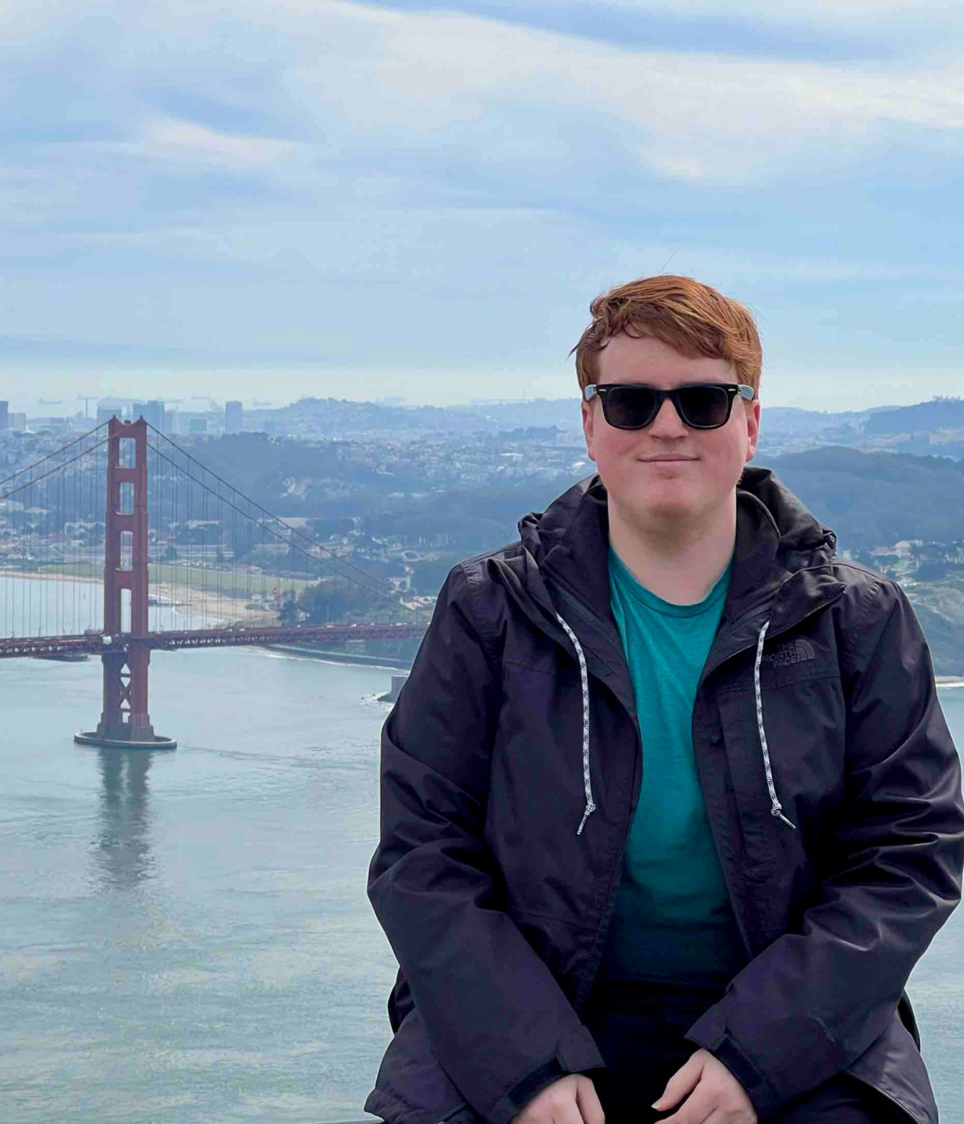 Jerry Duncan, a Machine Language Engineer at TikTok, sits and poses for a picture with the Golden Gate Bridge in the background.