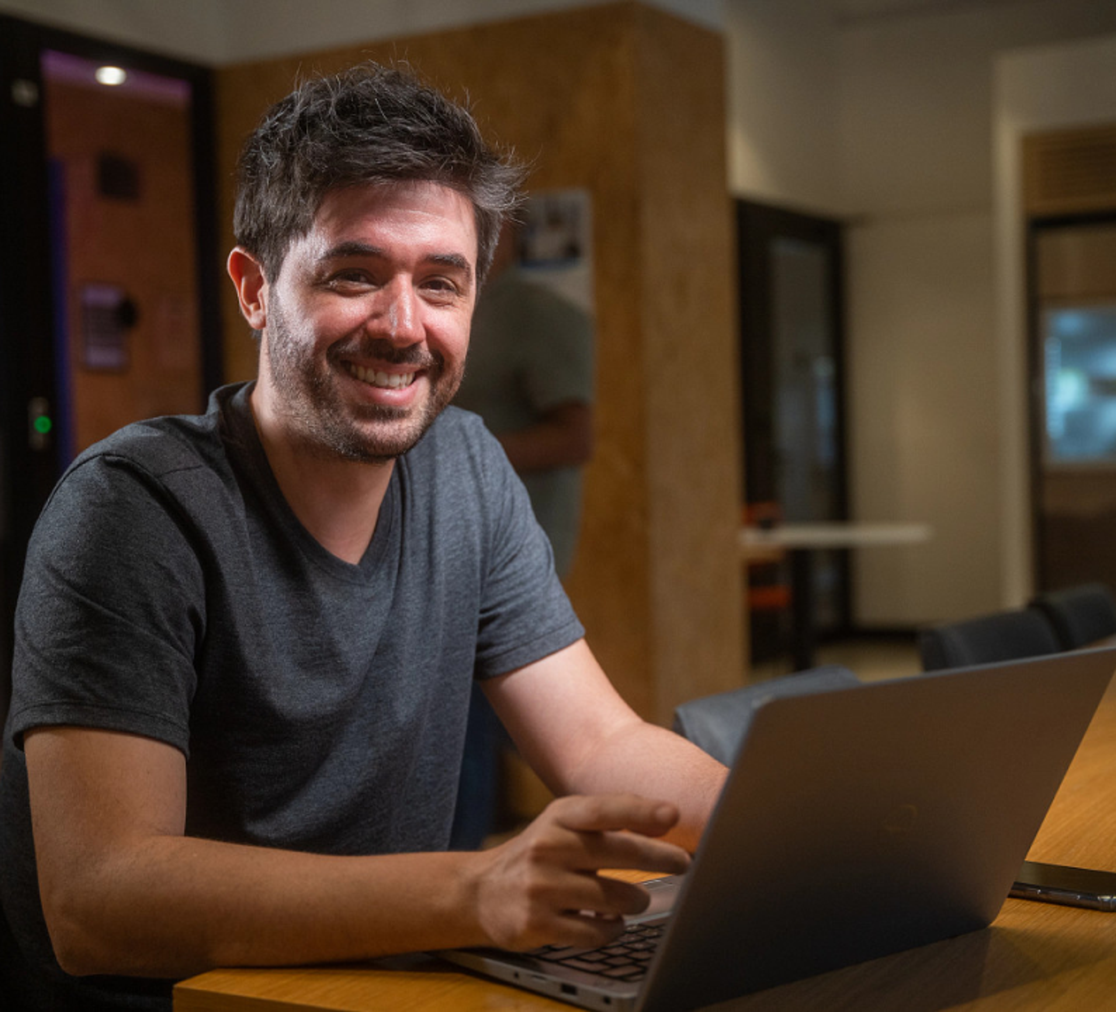 A young male ByteDance employee smiles as he works at his laptop.