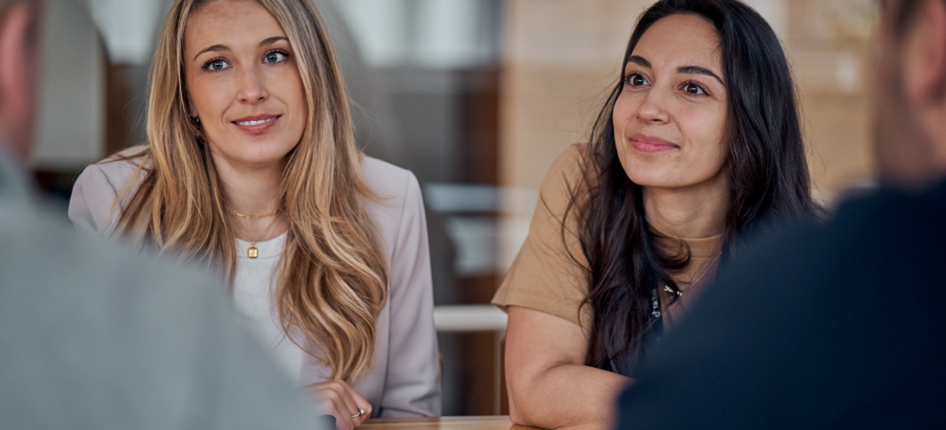 Two female TikTok employees look with interest at another colleague who is talking with them.