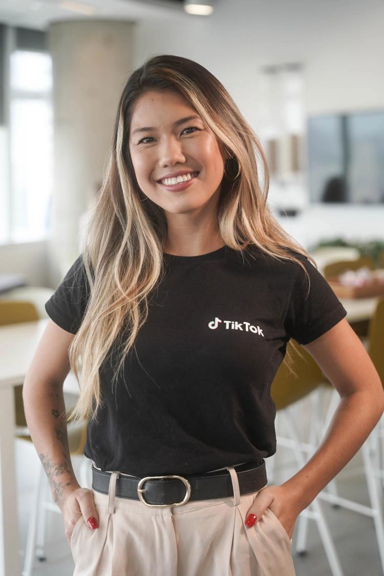 A young female Asian TikTok employee smiles as she poses for a picture.