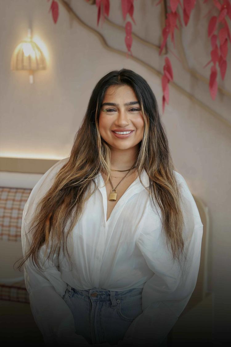 A young female TikTok employee with long blond hair smiles as she works on her laptop.