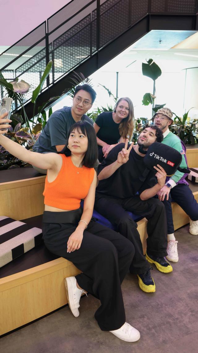 Group of diverse employees from TikTok Live team pose to take a selfie in the Sydney office