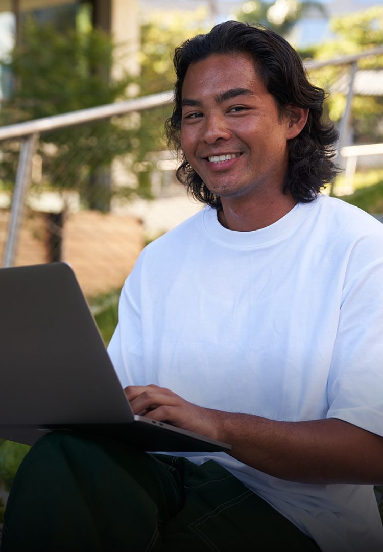 A young male Latino TikTok employee smiles as he works on his laptop.