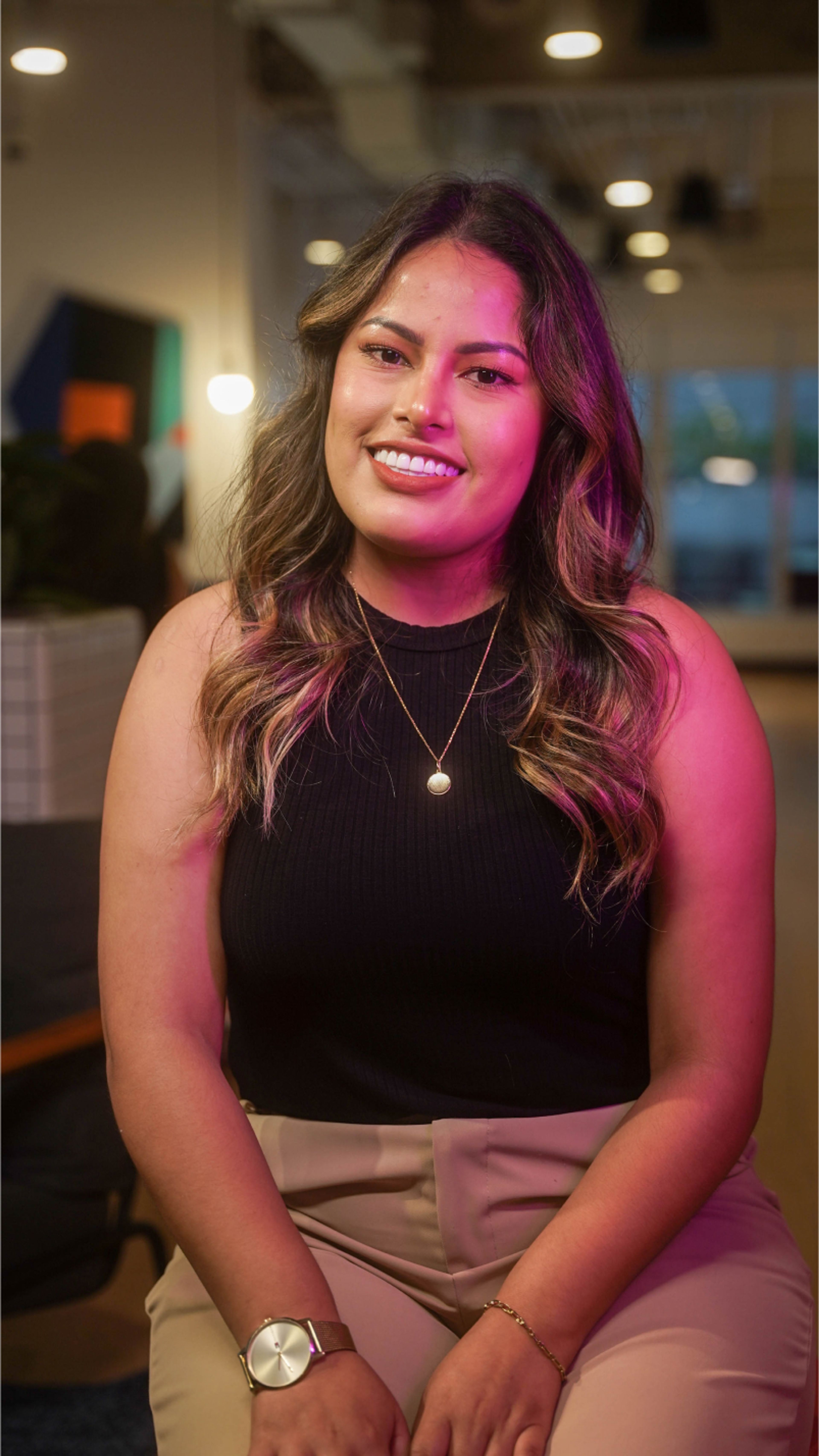 A young Latina ByteDance employee sits and smiles at the camera.