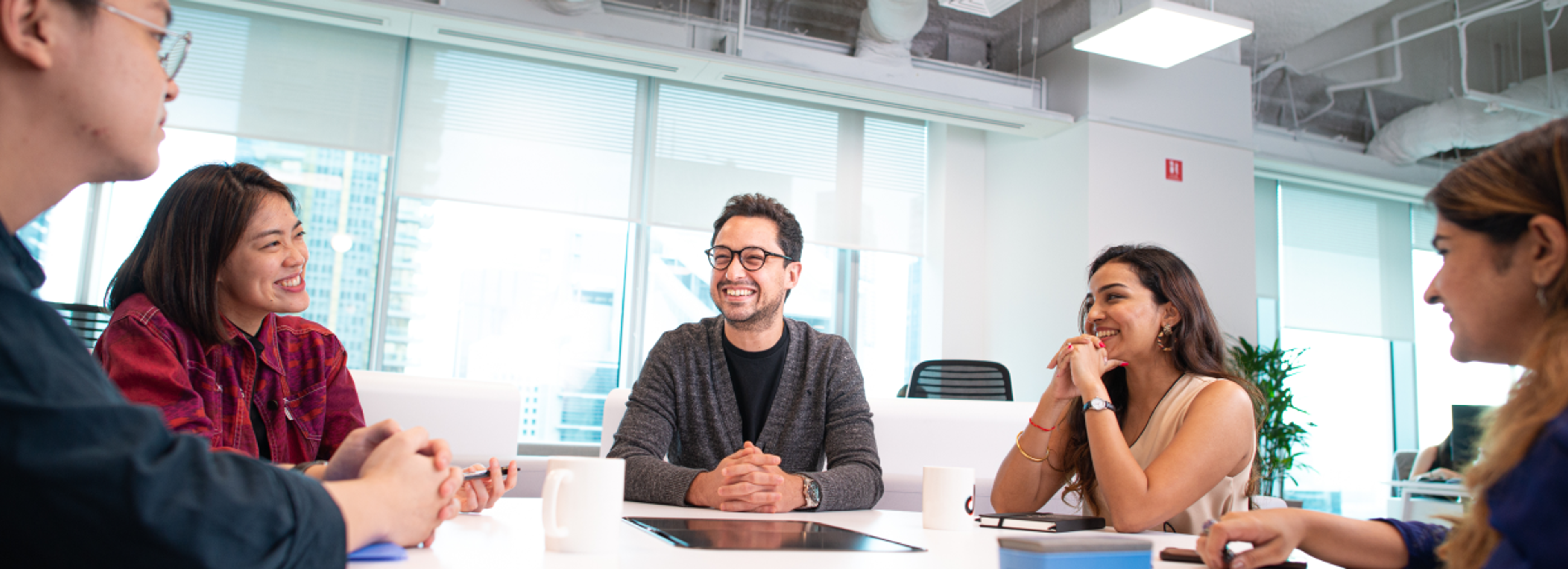 A group of male and female ByteDance employees work and laugh together in an office setting.