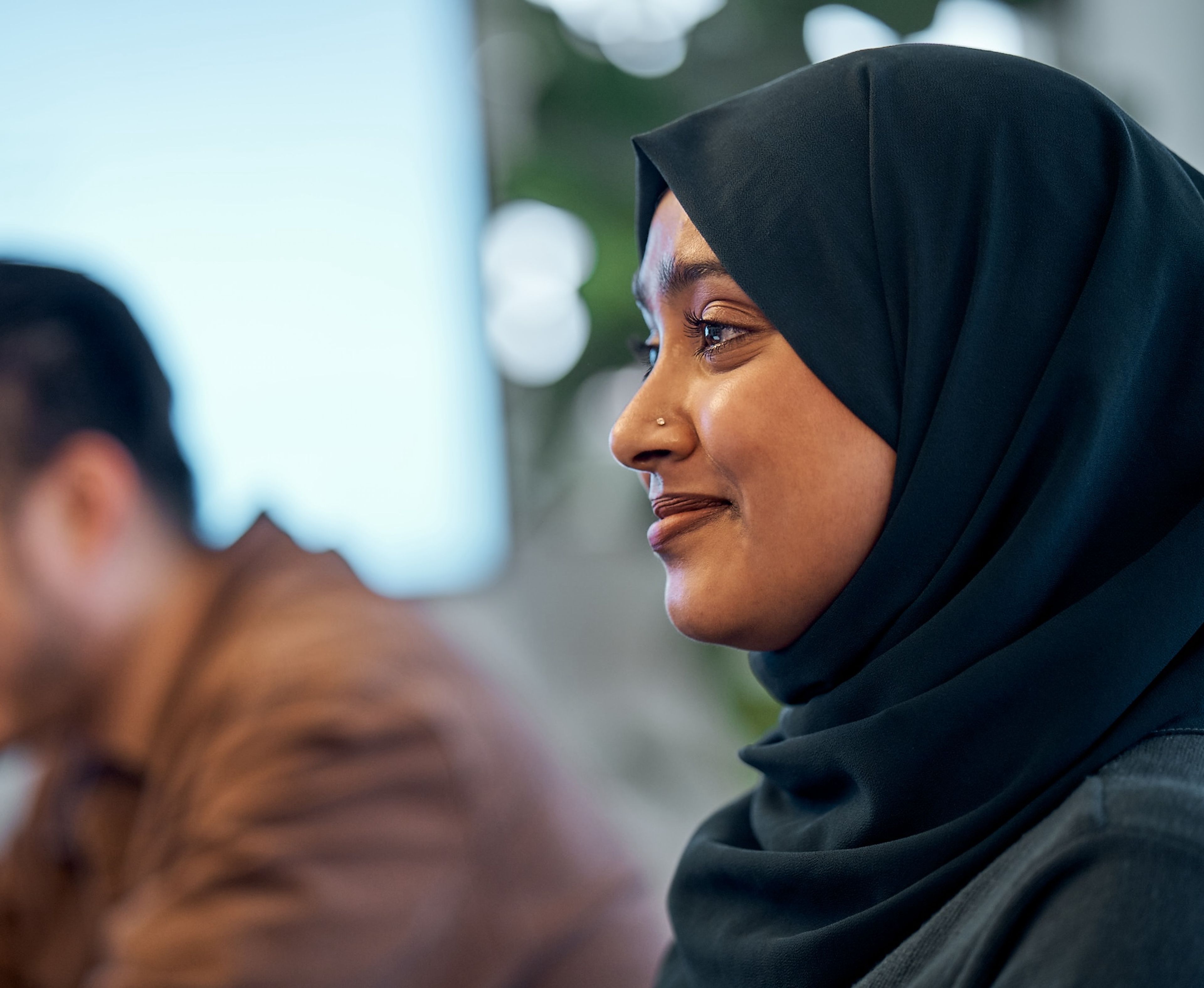 A female TikTok employee wearing a hijab sits and works at her computer.