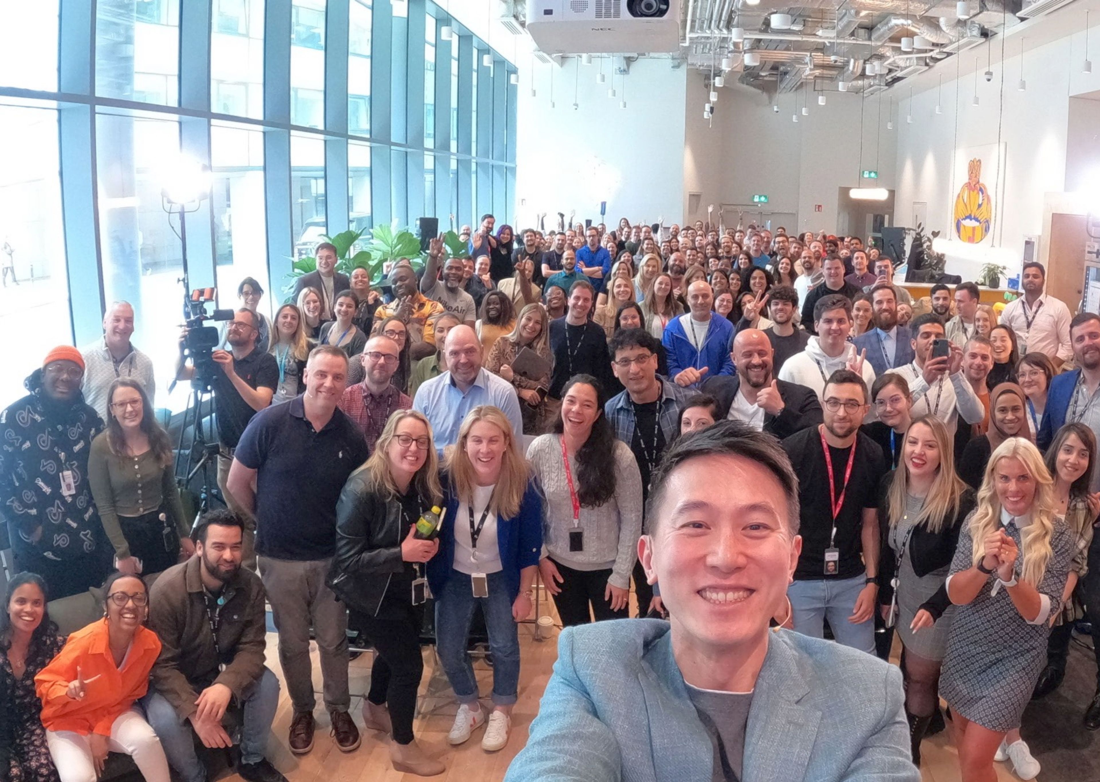 A room filled with TikTok employees who smile and pose for a group photo.