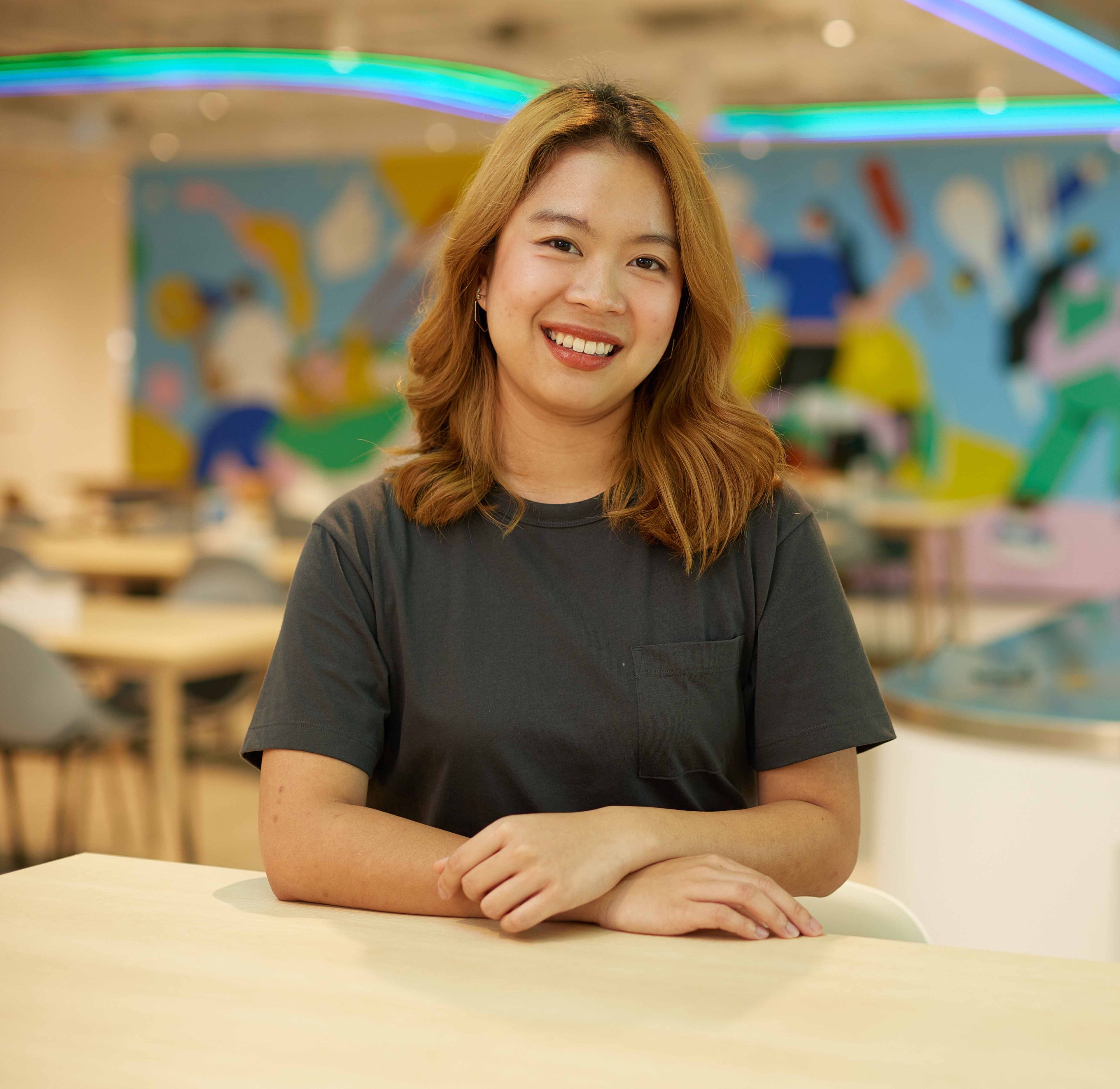 A ByteDance colleague from an office in Asia Pacific sits at a table and smiles at the camera