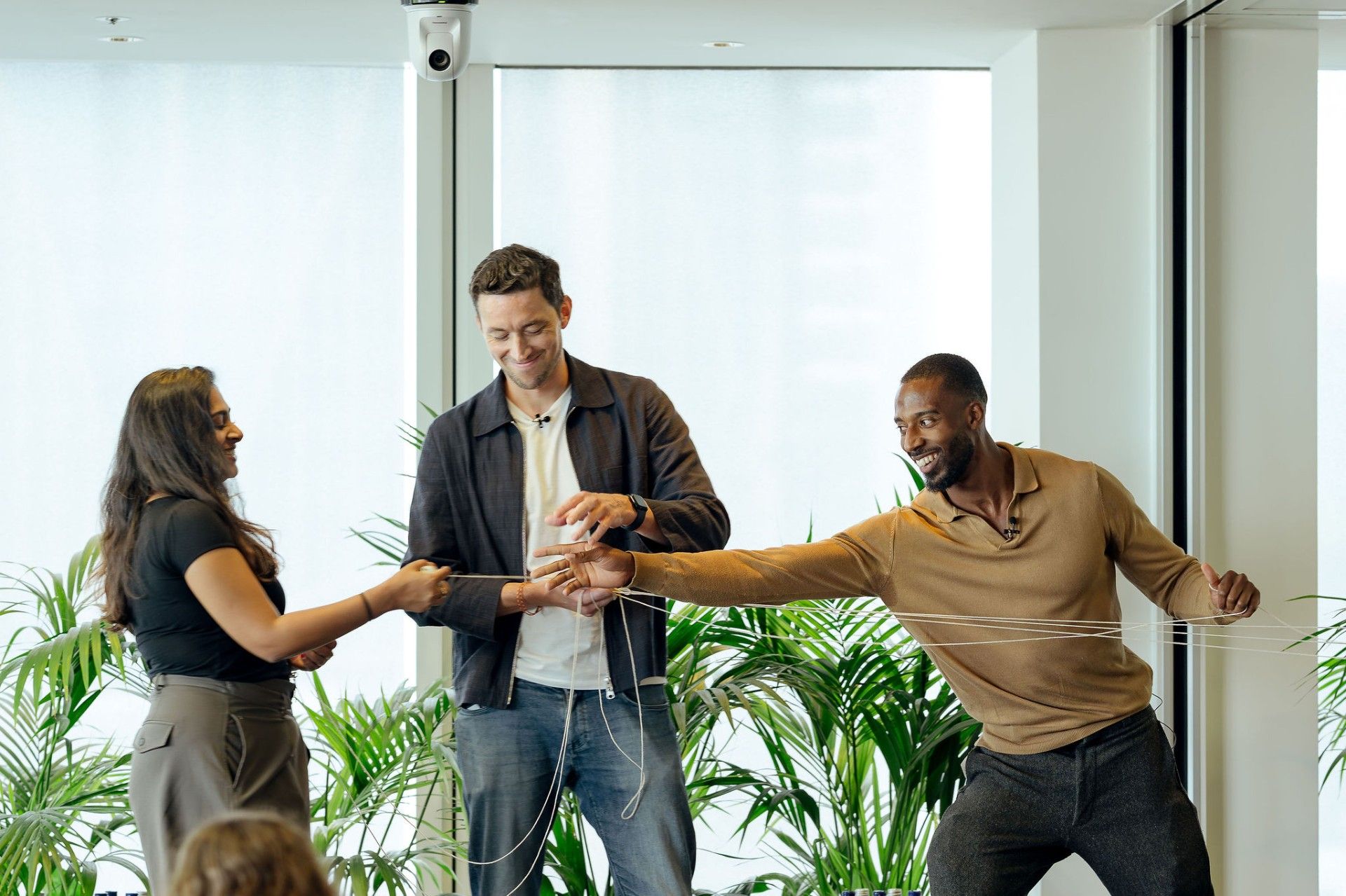 Team building exercise in an office with three people holding onto a piece of string