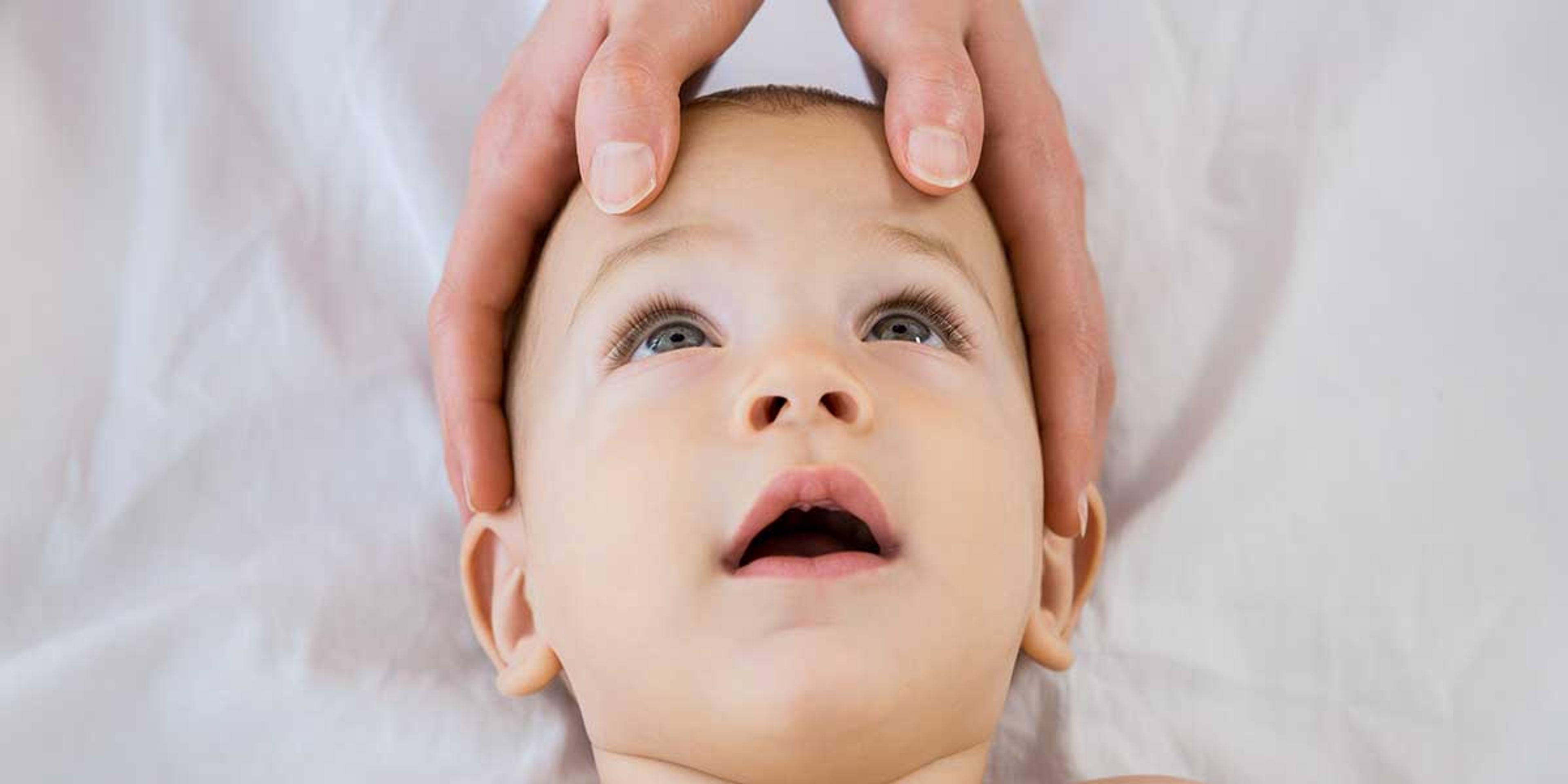 Gentle hands performing a mild pediatric chiropractic adjustment on a relaxed baby to help improve infant sleep problems naturally.