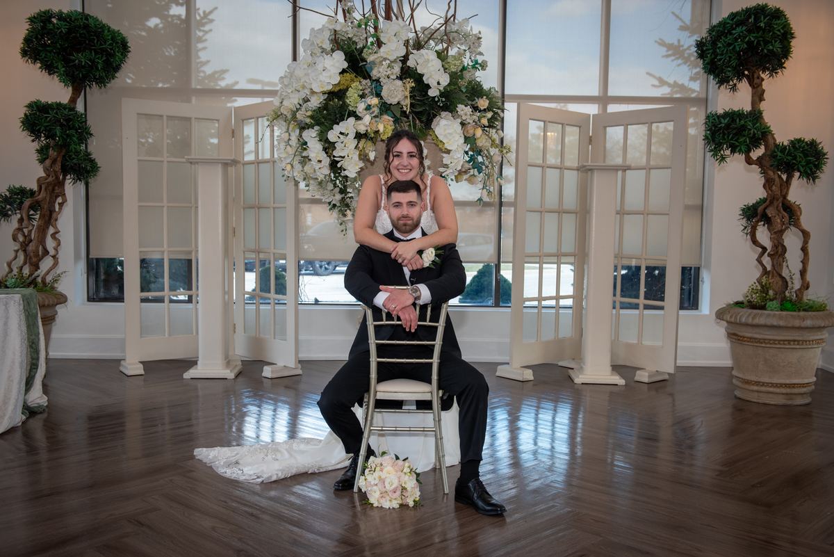 Danielle and Michael are captured in a joyful, posed moment inside an elegant hall during their wedding celebration.
